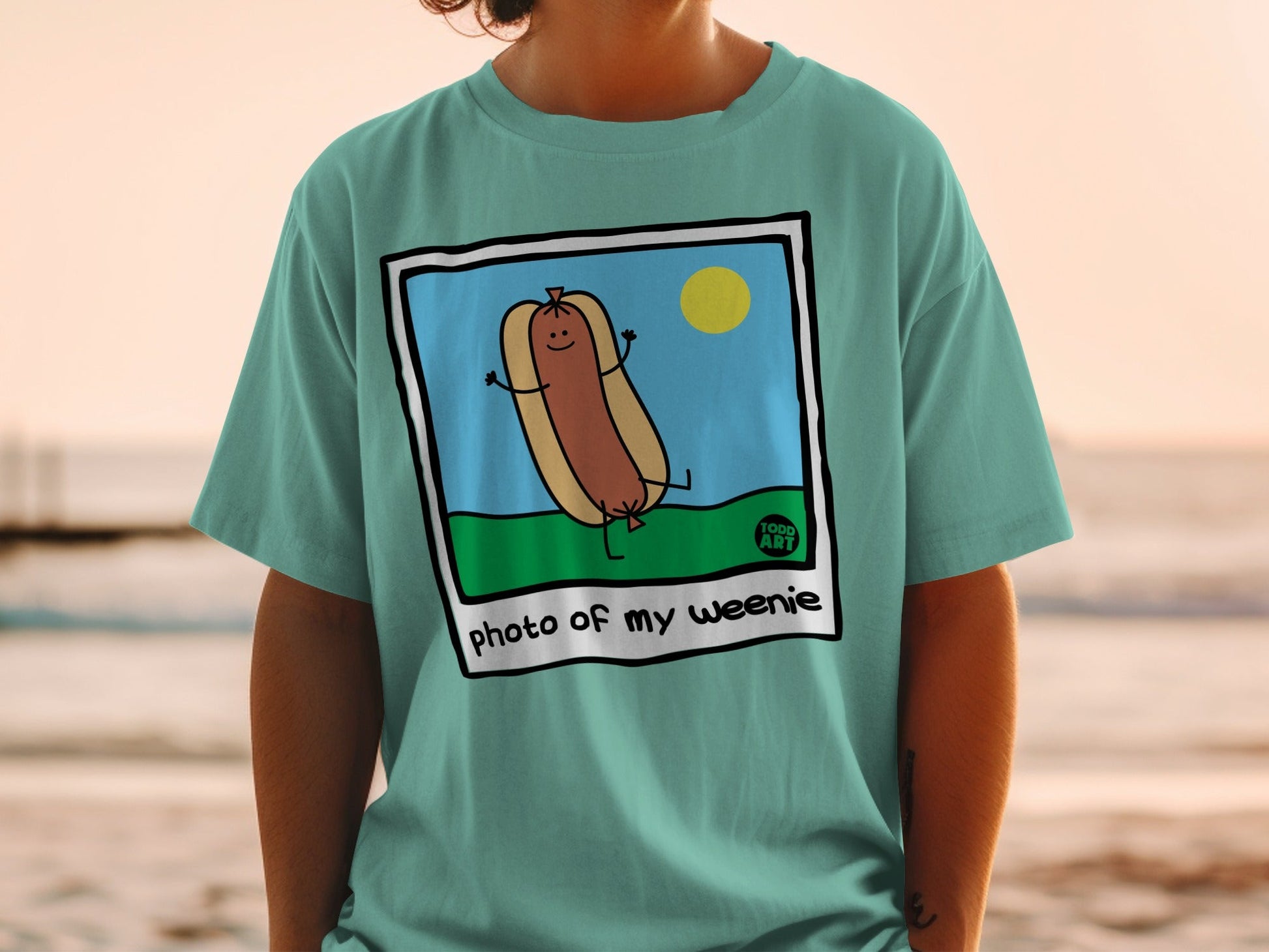 T-shirt with a cartoon hot dog in a bun, smiling, with the text "photo of my weenie".
