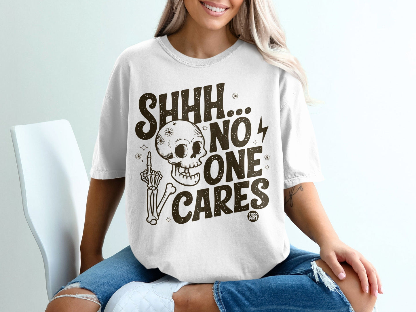 White t-shirt with "SHHH... NO ONE CARES" and skeleton graphic.