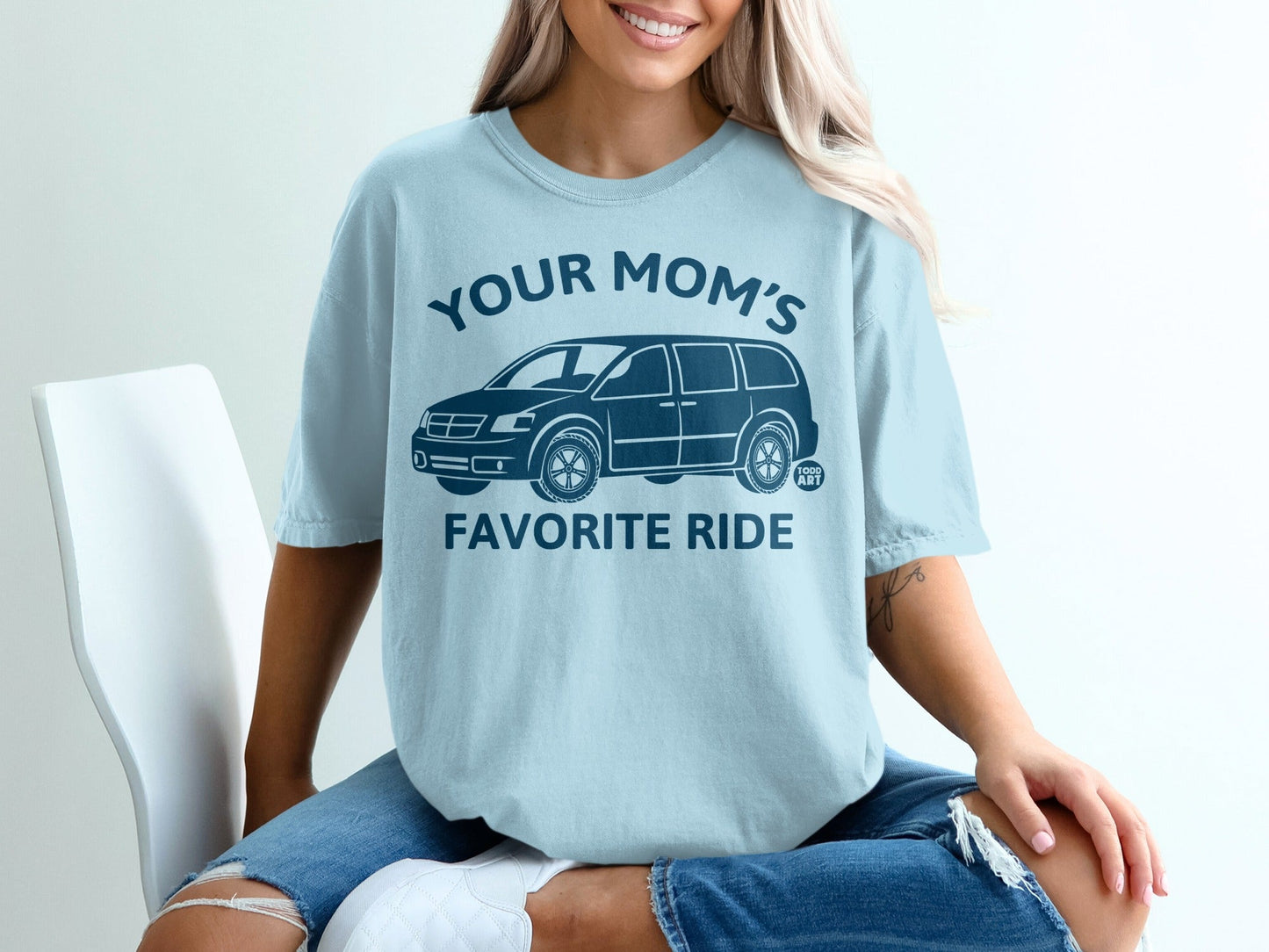 Light blue t-shirt with a dark blue graphic of a minivan and text "YOUR MOM'S FAVORITE RIDE".