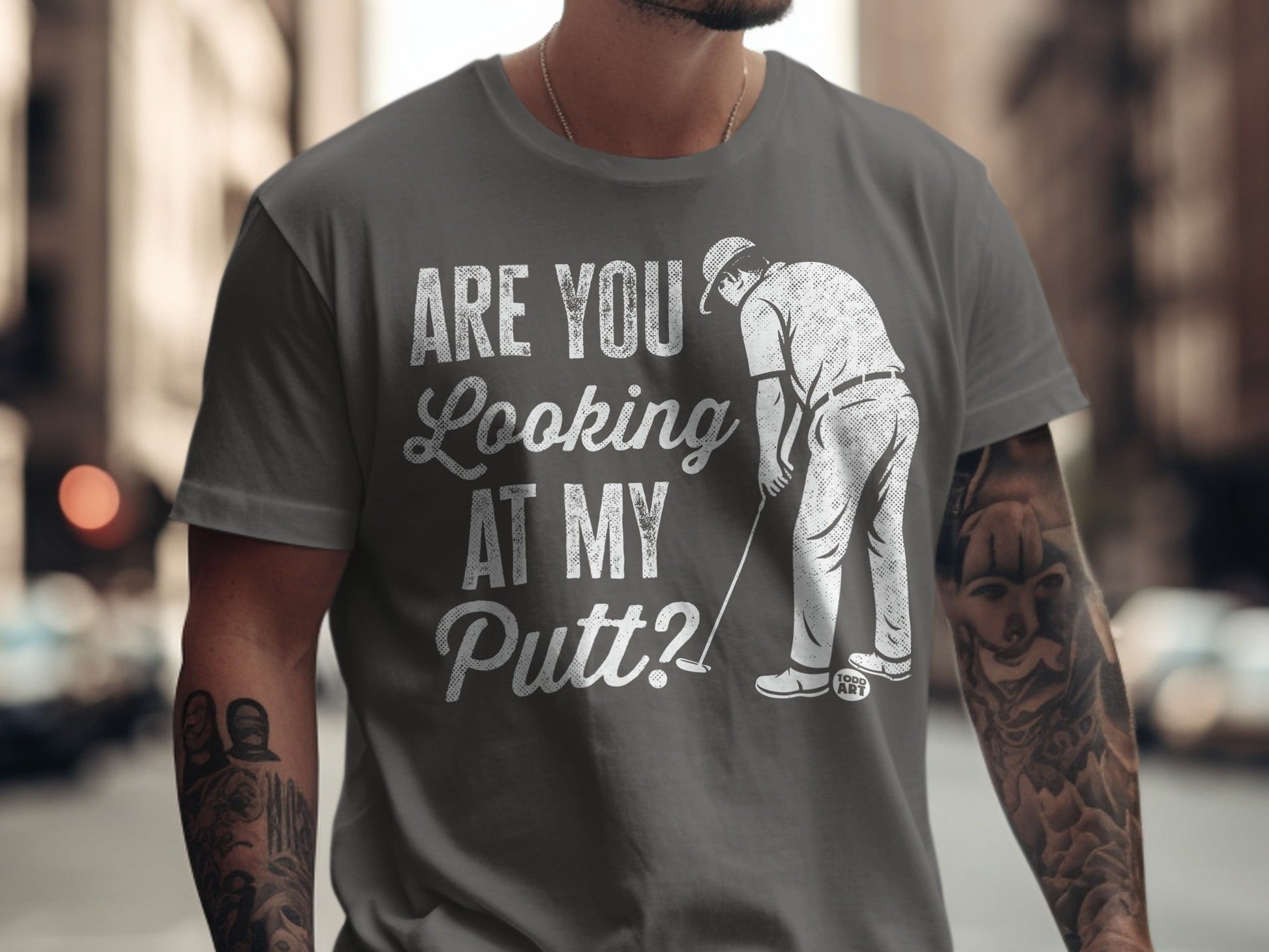 Man in grey t-shirt with "ARE YOU LOOKING AT MY PUTT?" text and golfer graphic.