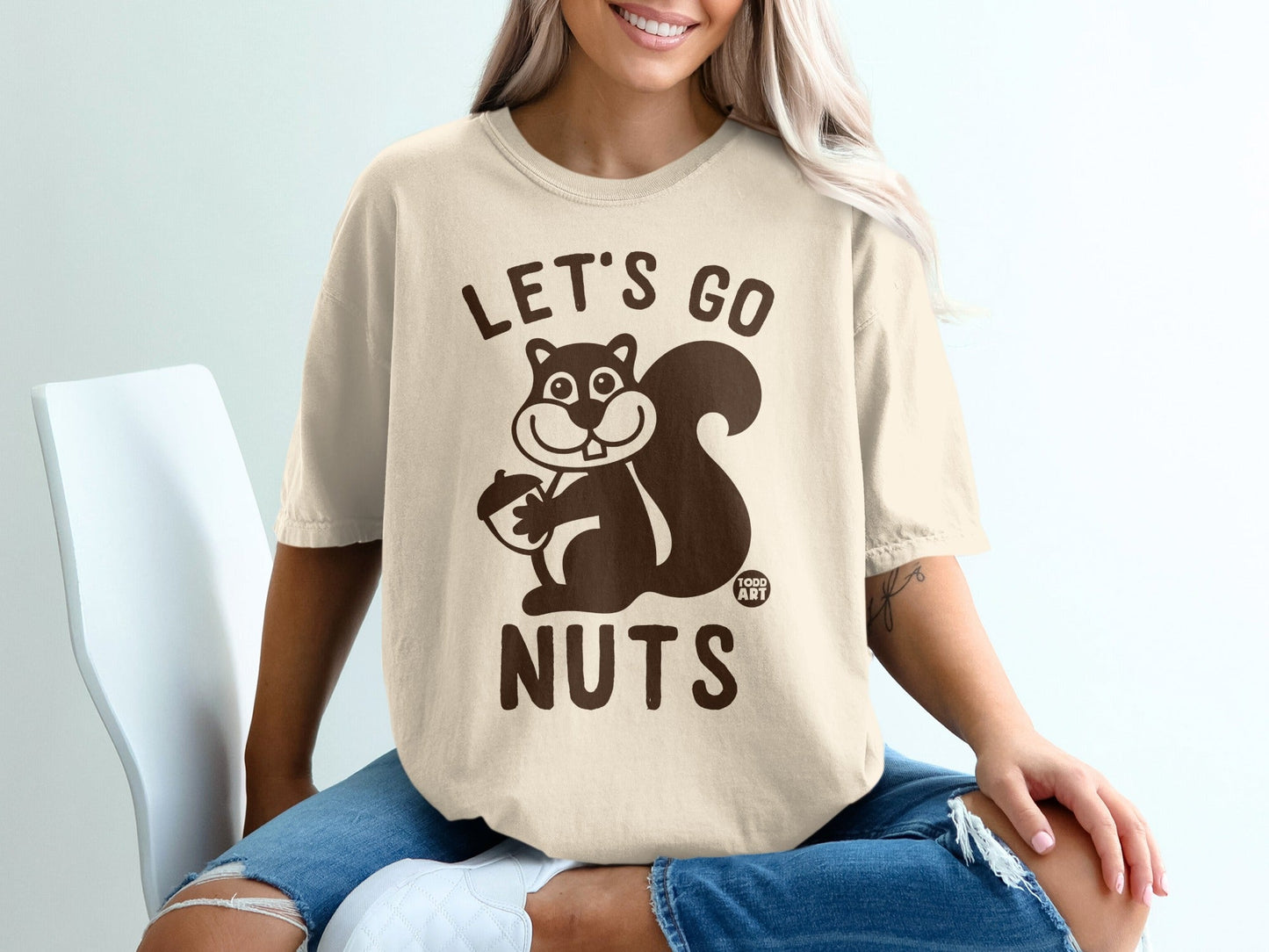 Tan t-shirt with "Let's Go Nuts" and a cartoon squirrel holding an acorn.