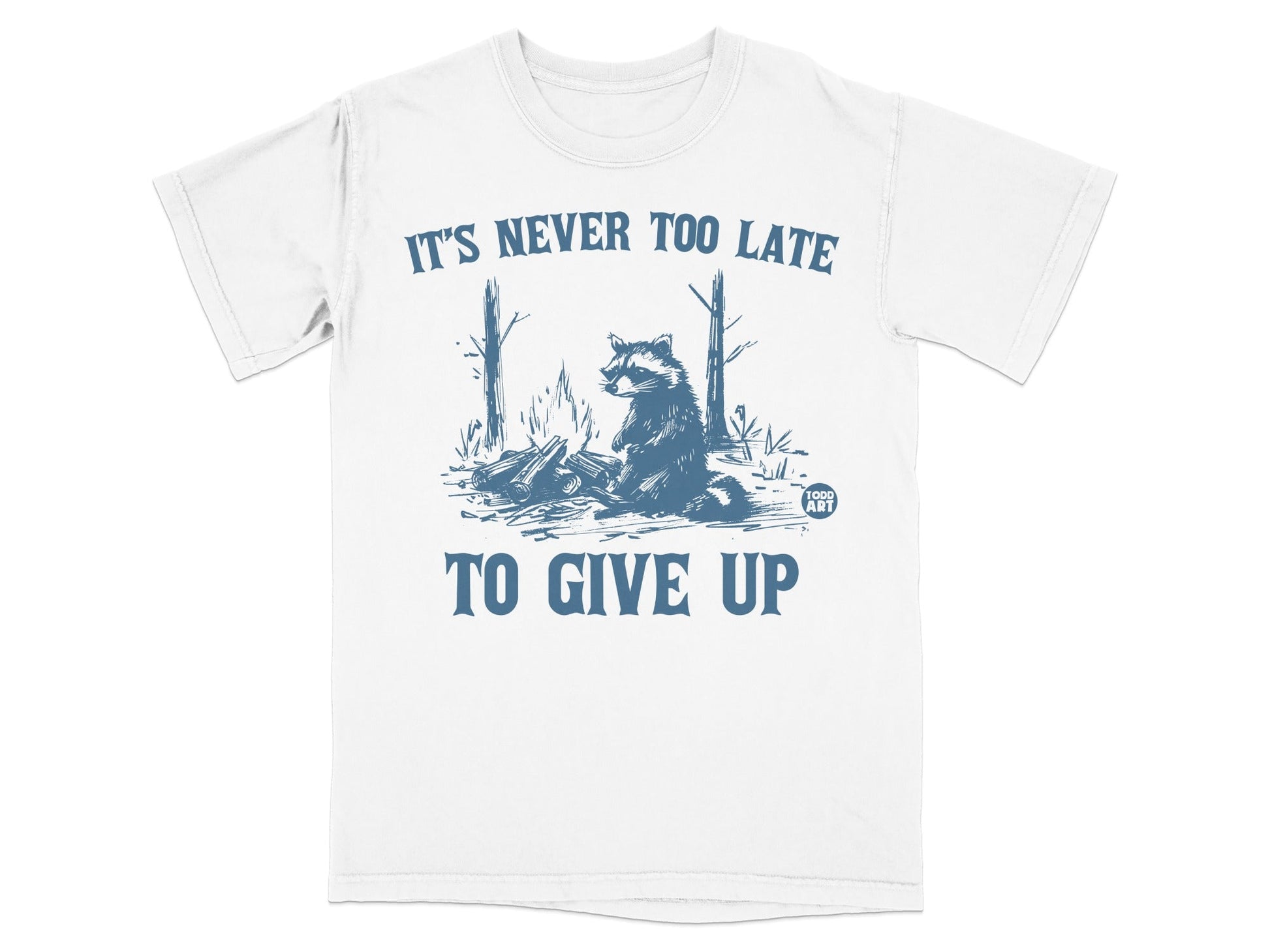 White t-shirt with raccoon, campfire, and "It's Never Too Late to Give Up" text.