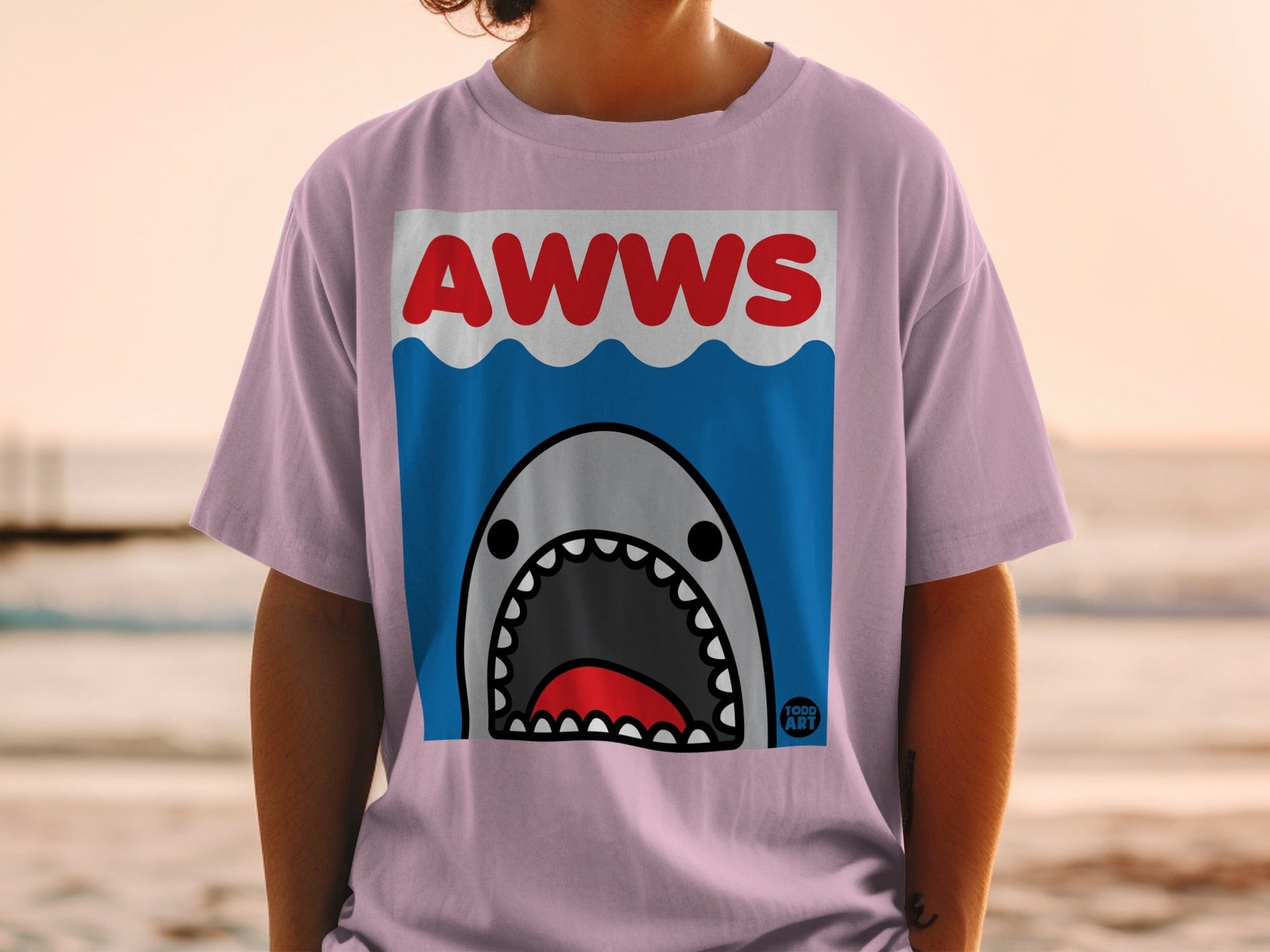 Pink t-shirt with a cartoon shark and "AWWS" text.