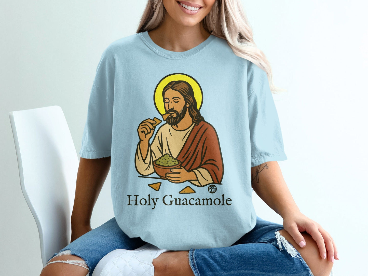 Jesus with halo eating guacamole and tortilla chips, "Holy Guacamole" text.