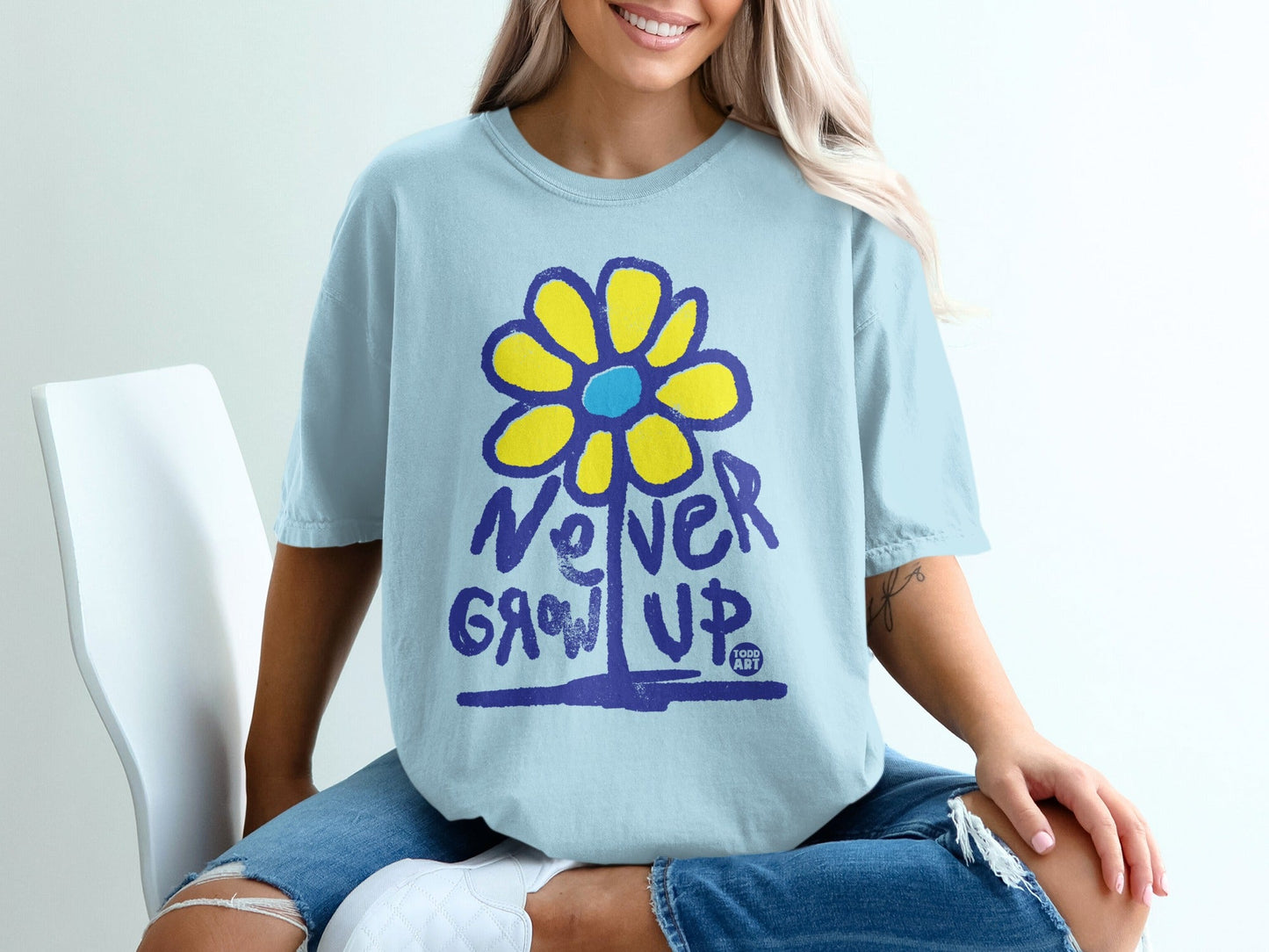 Light blue t-shirt with yellow flower graphic and "Never Grow Up" text.