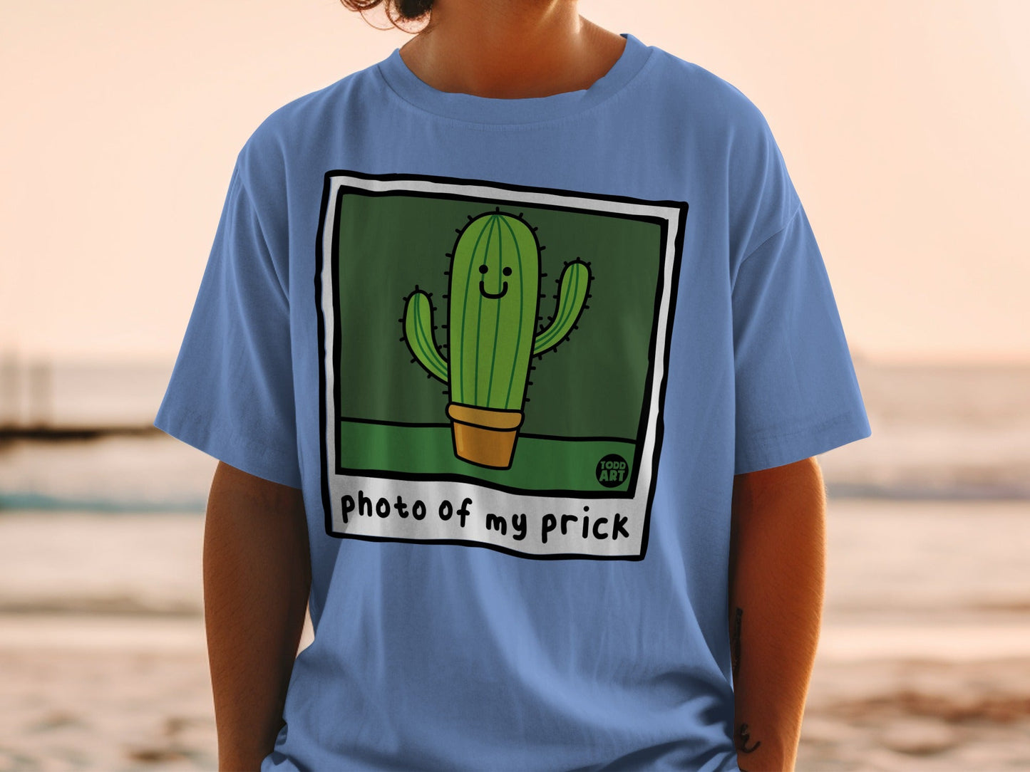 Blue t-shirt with a cartoon cactus in a pot that says "photo of my prick".