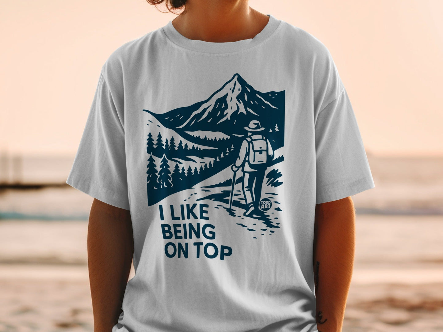 White t-shirt with mountain hiker graphic and "I like being on top" text.