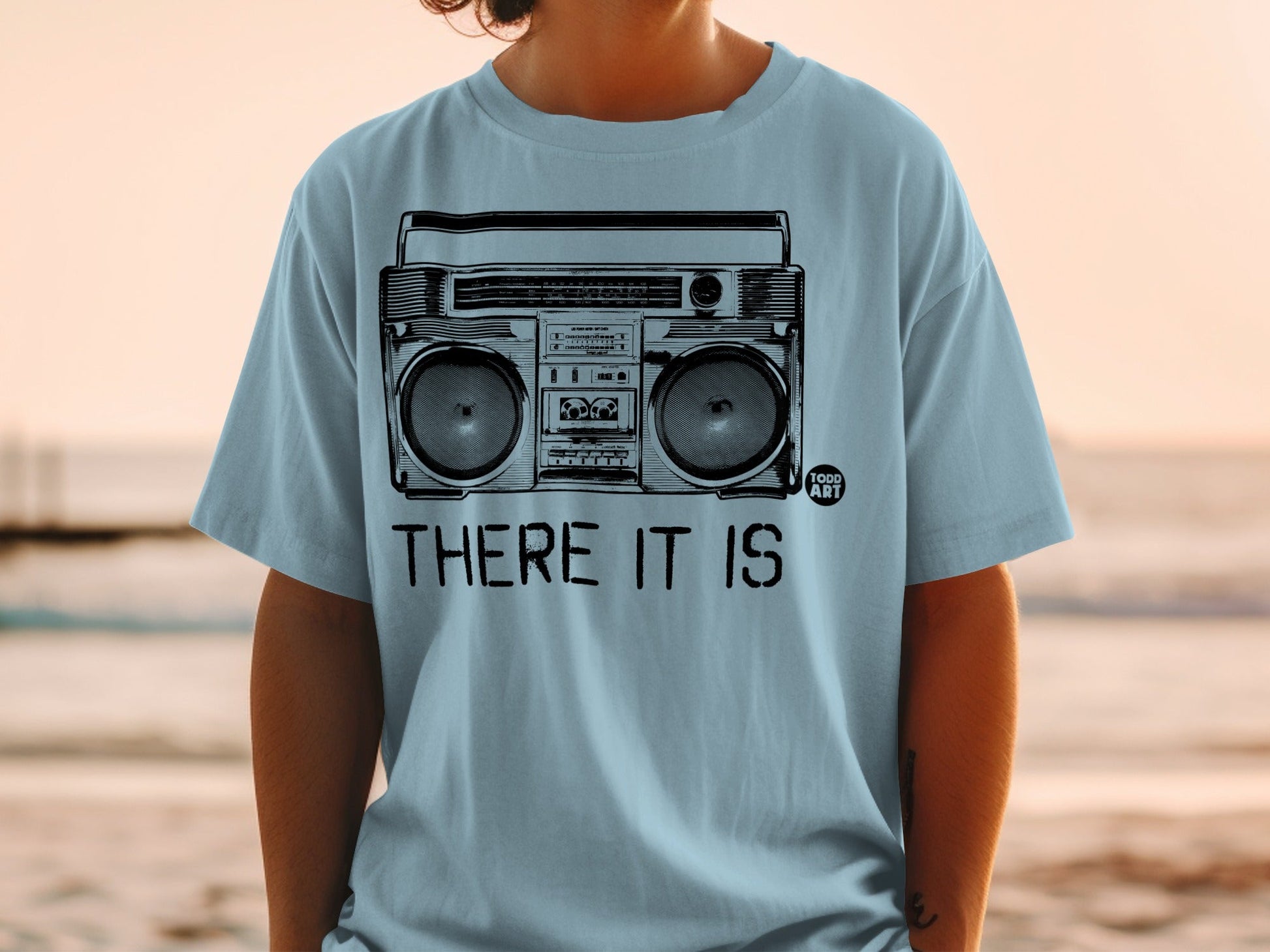 Light blue t-shirt with a graphic of a boombox and the text "THERE IT IS".