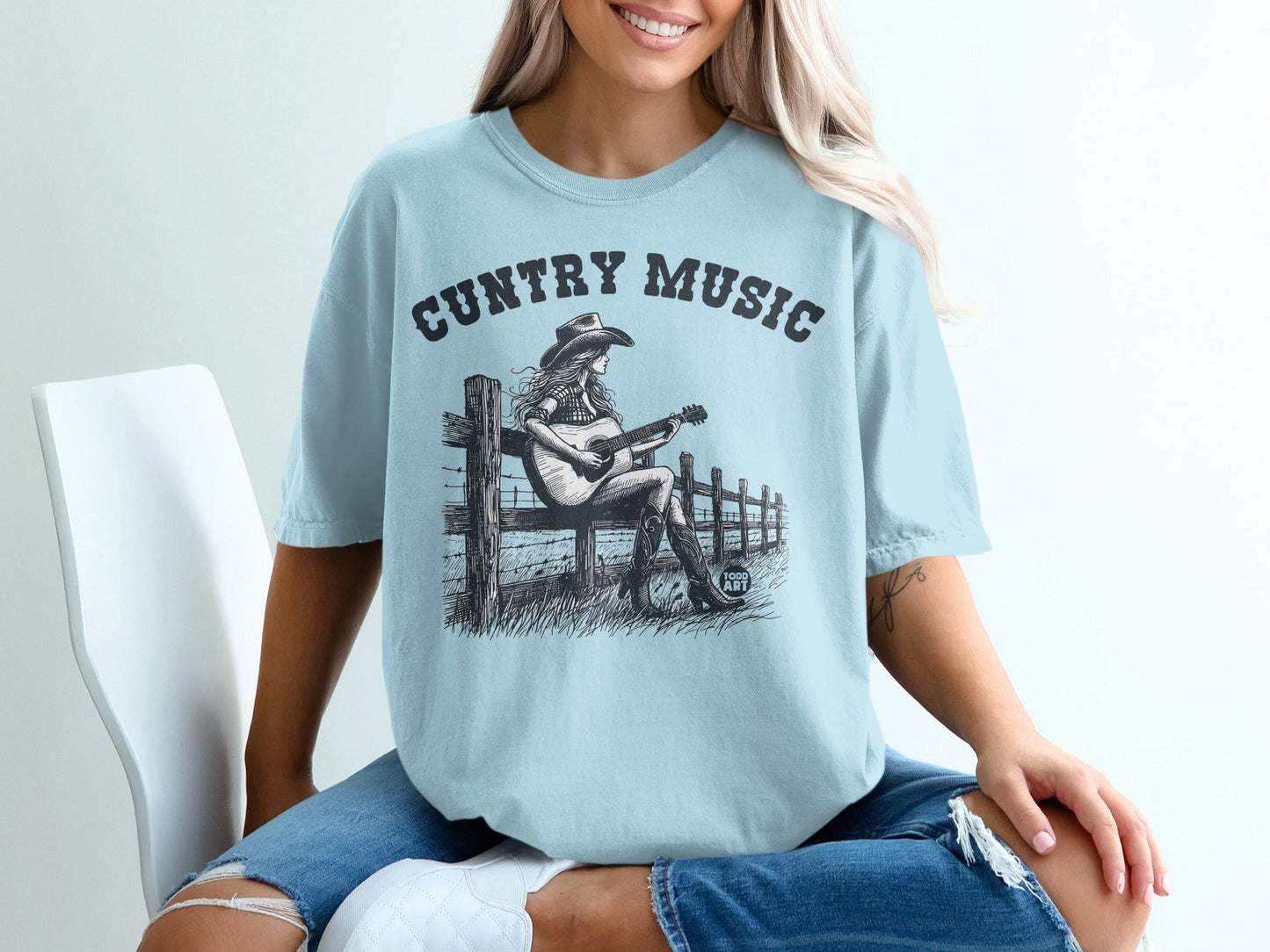 Light blue t-shirt with "Country Music" graphic and woman playing guitar.