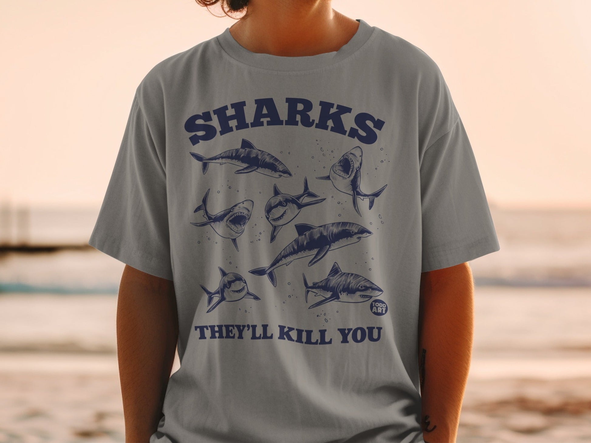 T-shirt with a dark blue graphic of several sharks and text "SHARKS THEY'LL KILL YOU".