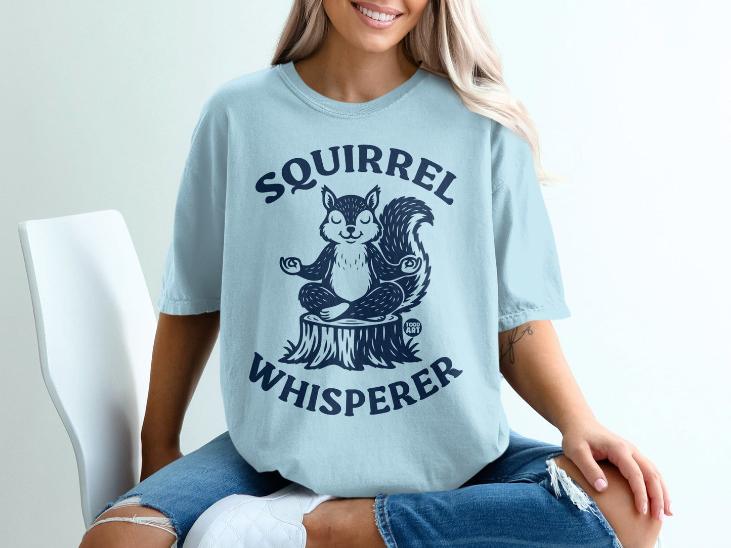 Light blue t-shirt with a meditating squirrel on a tree stump graphic and text.