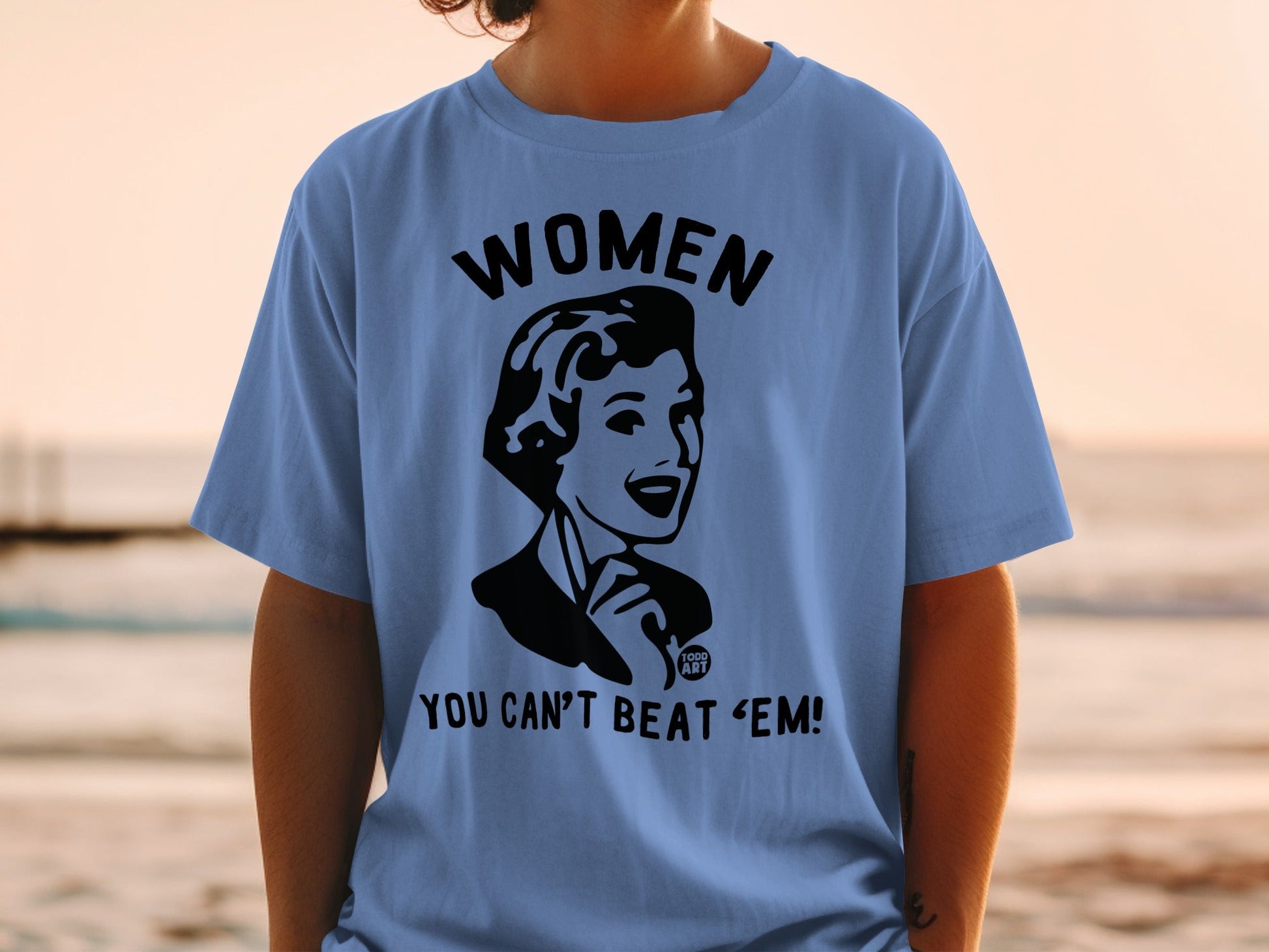 Black graphic of a woman with "WOMEN YOU CAN'T BEAT 'EM!" text on a blue t-shirt.