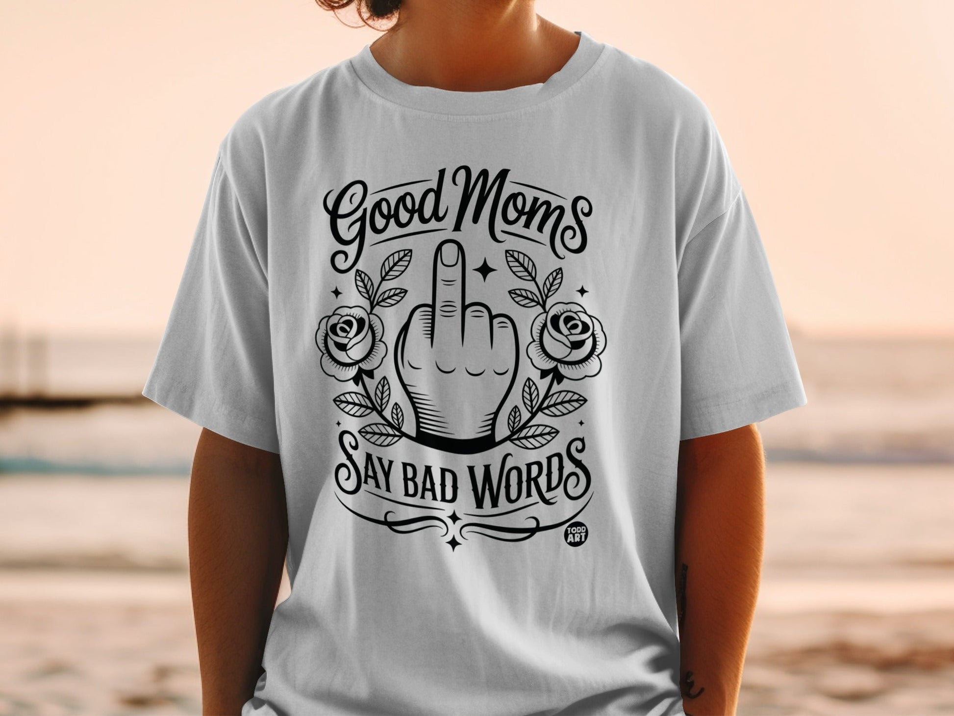 White t-shirt with "Good Moms Say Bad Words" text and floral accents.