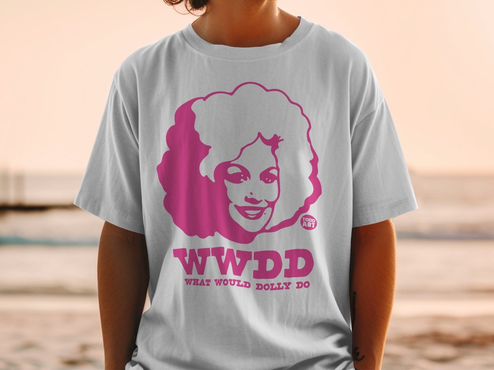 Pink graphic t-shirt with WWDD What Would Dolly Do? text and Dolly Parton illustration.