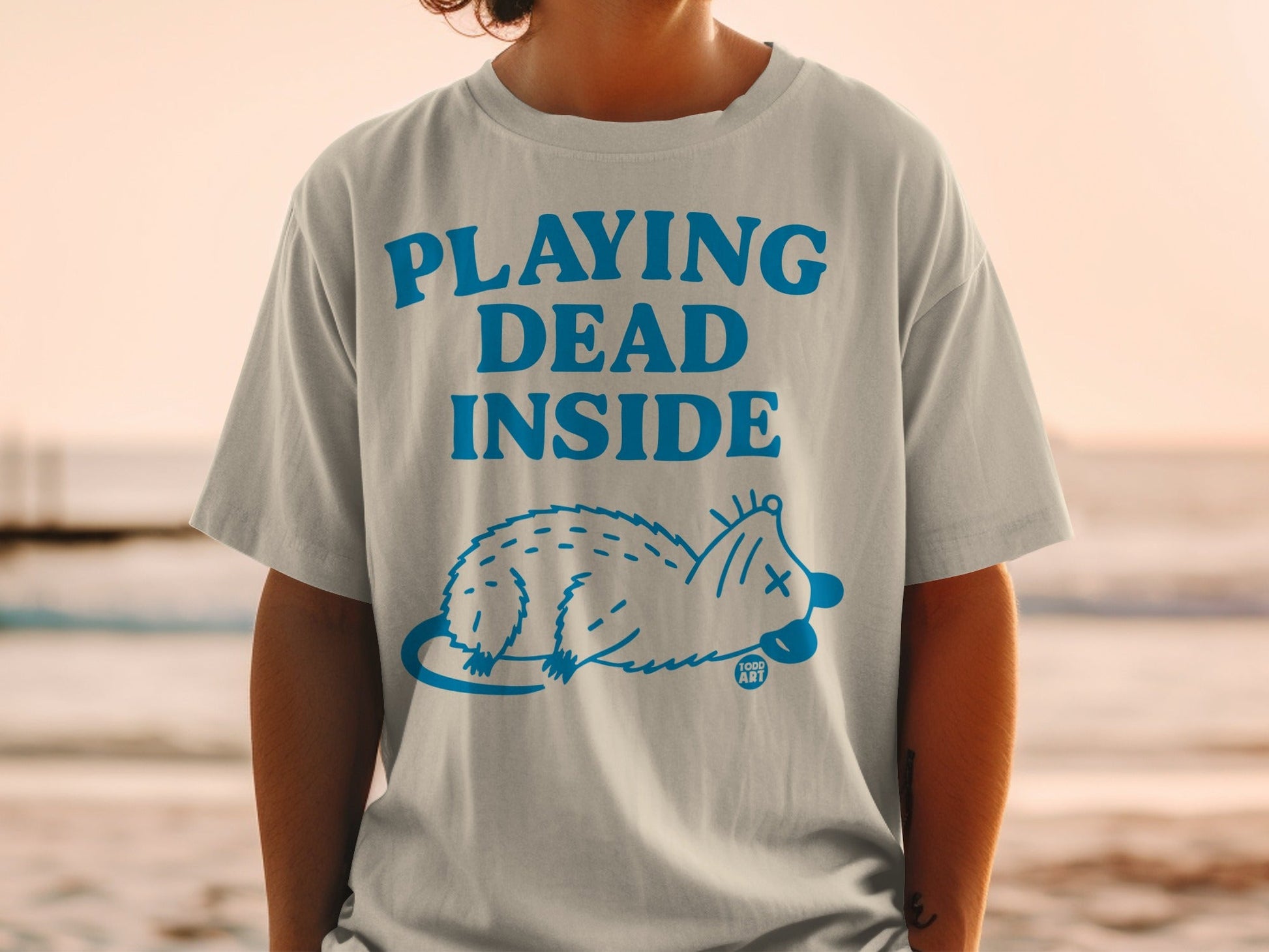 Light gray t-shirt with "PLAYING DEAD INSIDE" and a blue possum graphic.