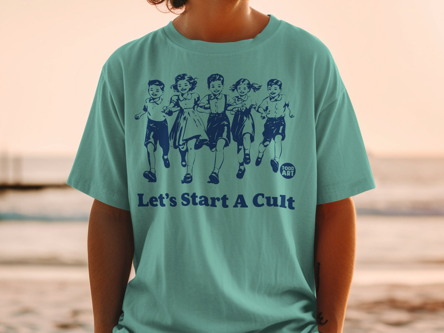 Teal t-shirt with five running children illustration and "Todd Art" and "Let's Start A Cult" text.