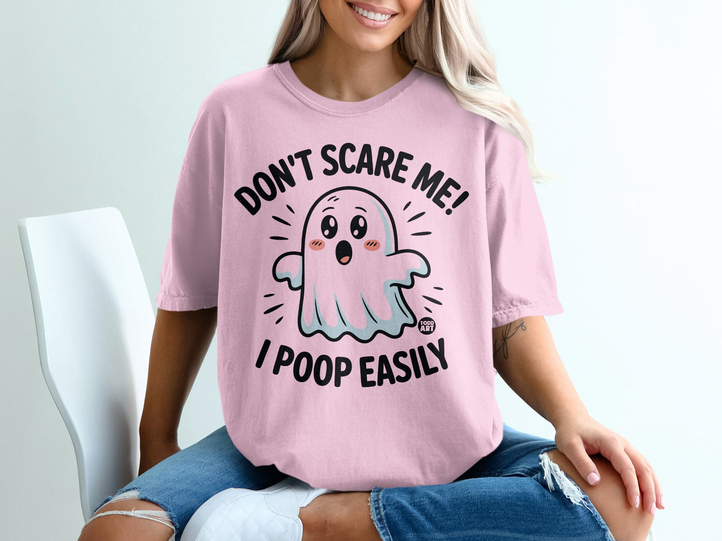 Pink t-shirt with cartoon ghost saying "Don't scare me! I poop easily."