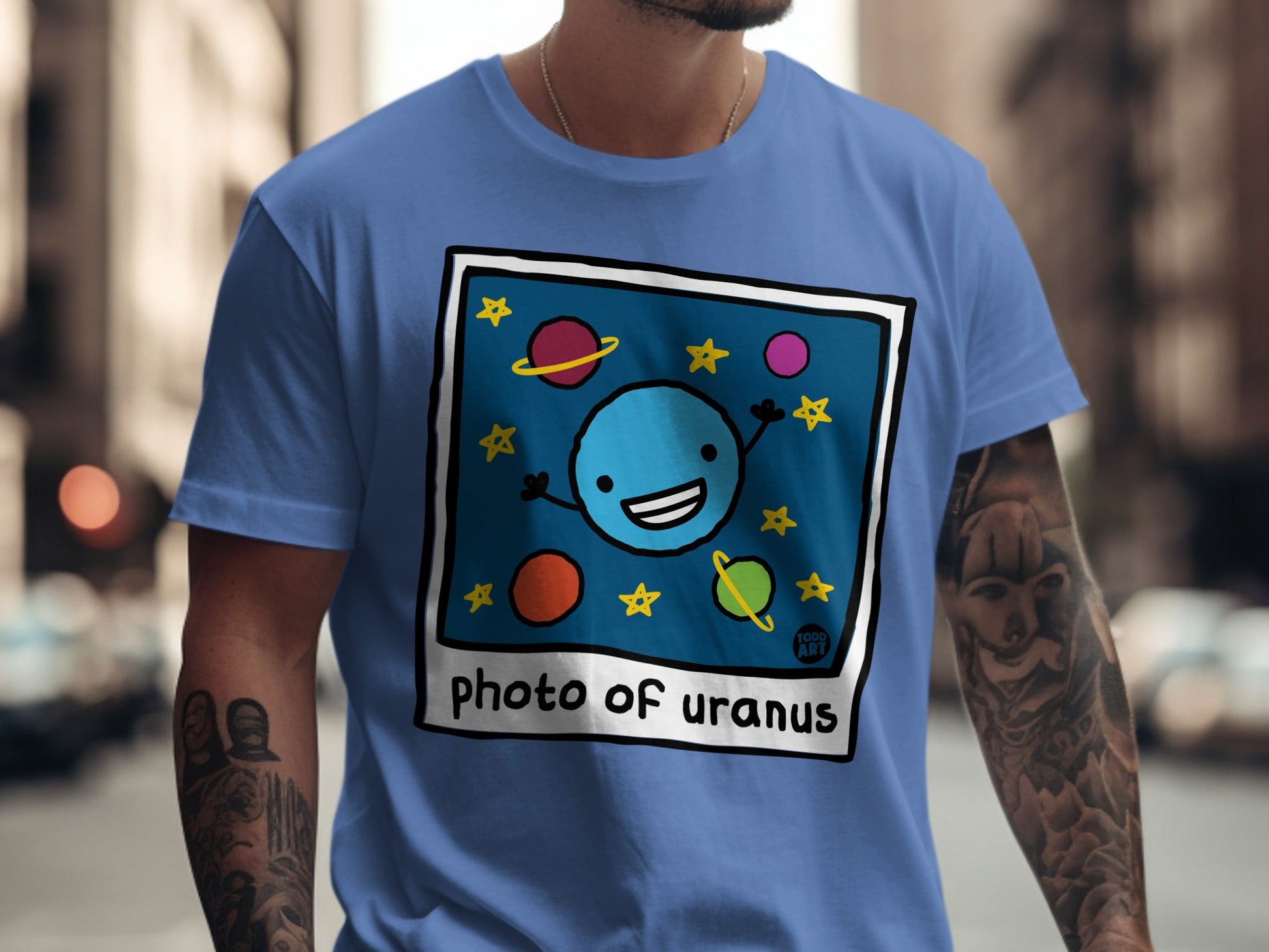 Blue t-shirt with a cartoon drawing of Uranus and stars.