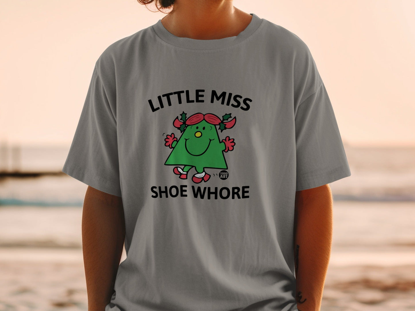 Little Miss Shoe Whore cartoon character on a grey t-shirt.