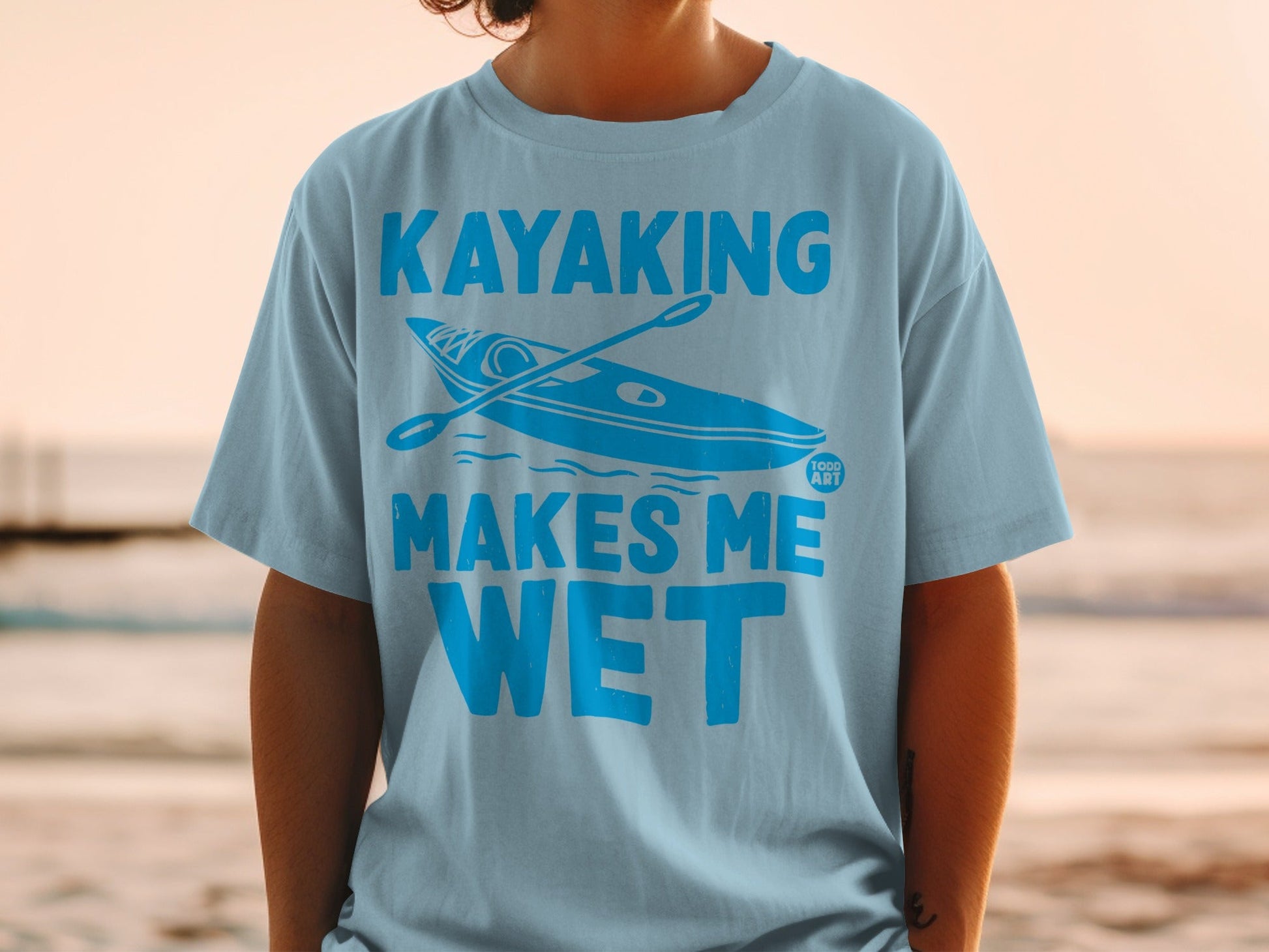Light blue t-shirt with "Kayaking Makes Me Wet" text and kayak graphic.