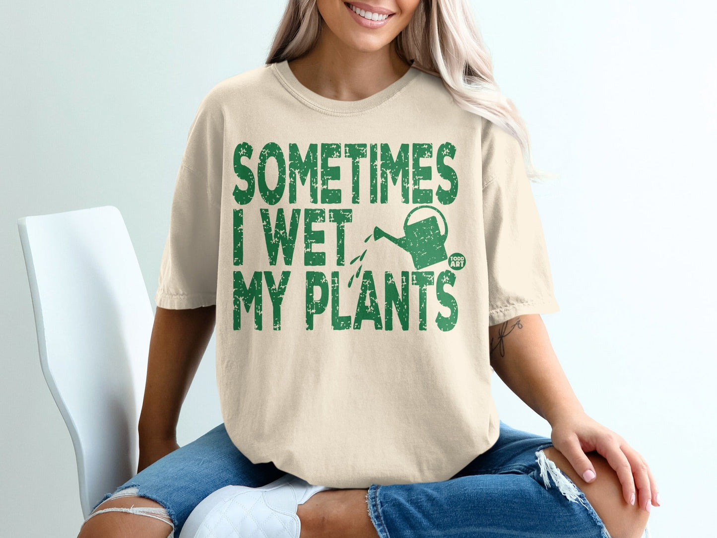 Cream t-shirt with green text "SOMETIMES I WET MY PLANTS" and watering can graphic.