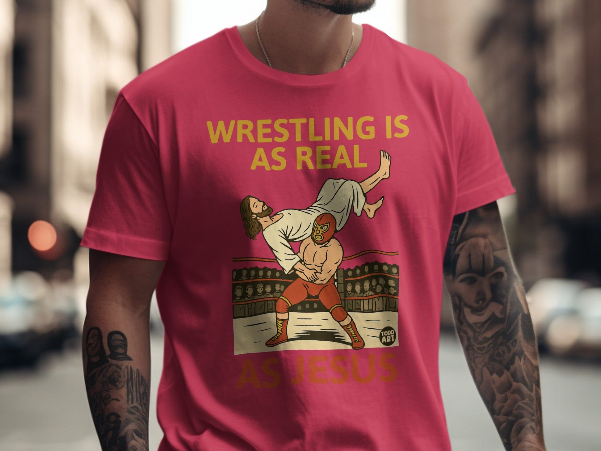 T-shirt with yellow text "WRESTLING IS REAL AS JESUS" and wrestling graphic.