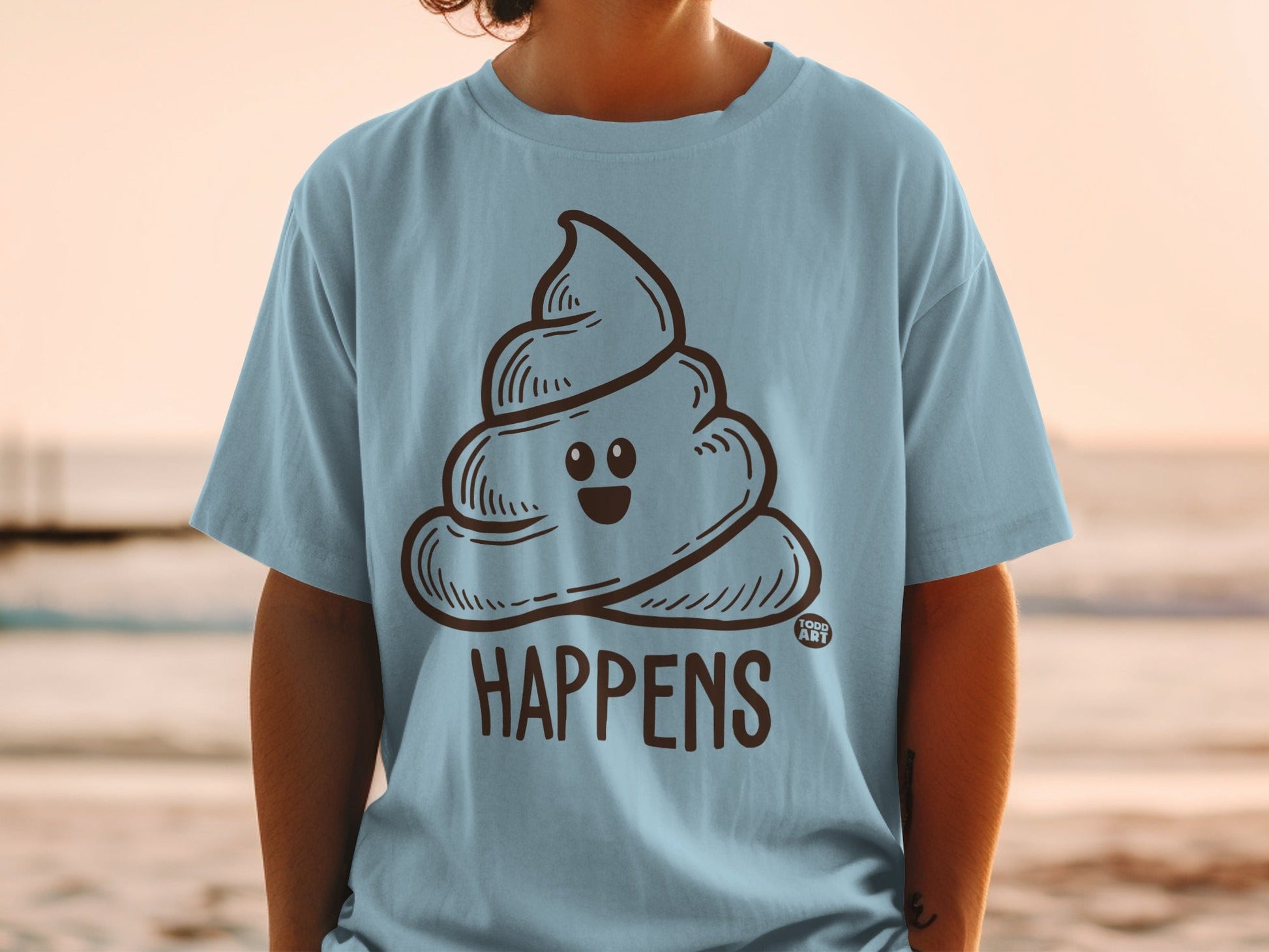 Light blue t-shirt with a cartoon smiling poop emoji and "HAPPENS" text.