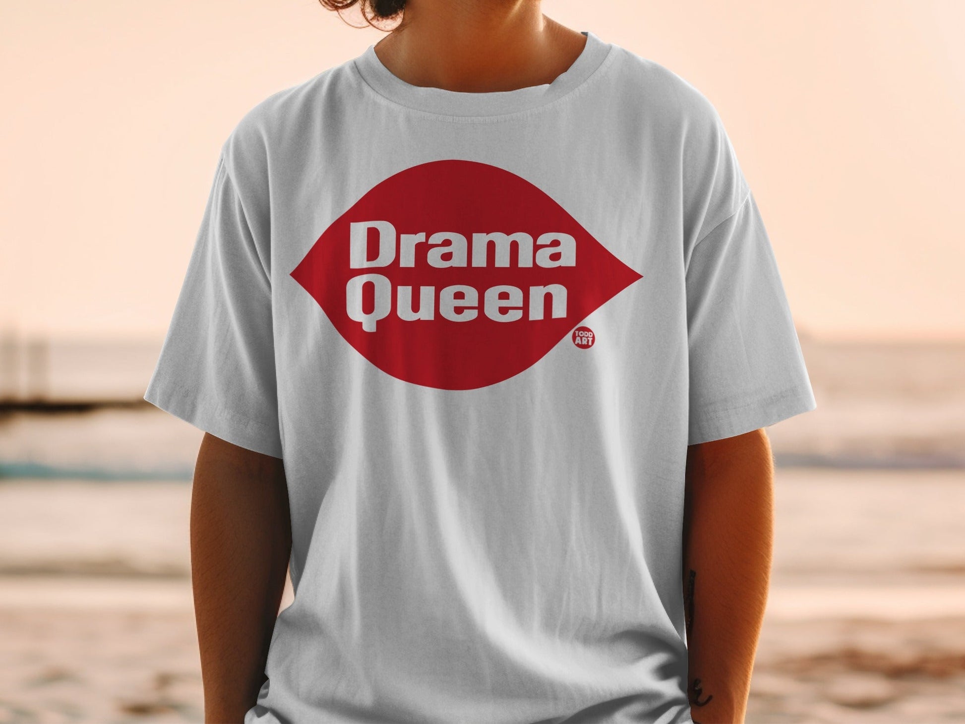 White t-shirt with red "Drama Queen" diamond logo and smaller "ART" logo.