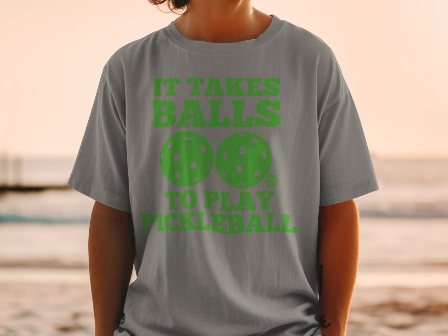 Gray t-shirt with green text and pickleball graphics reading "It takes balls to play pickleball."