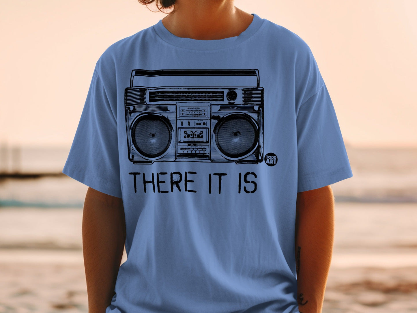 Blue t-shirt with a black graphic of a boombox and text "THERE IT IS".