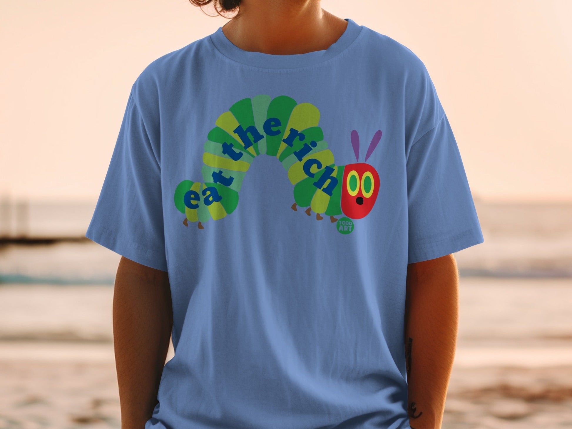 Blue t-shirt with The Very Hungry Caterpillar graphic spelling "eat the rich".