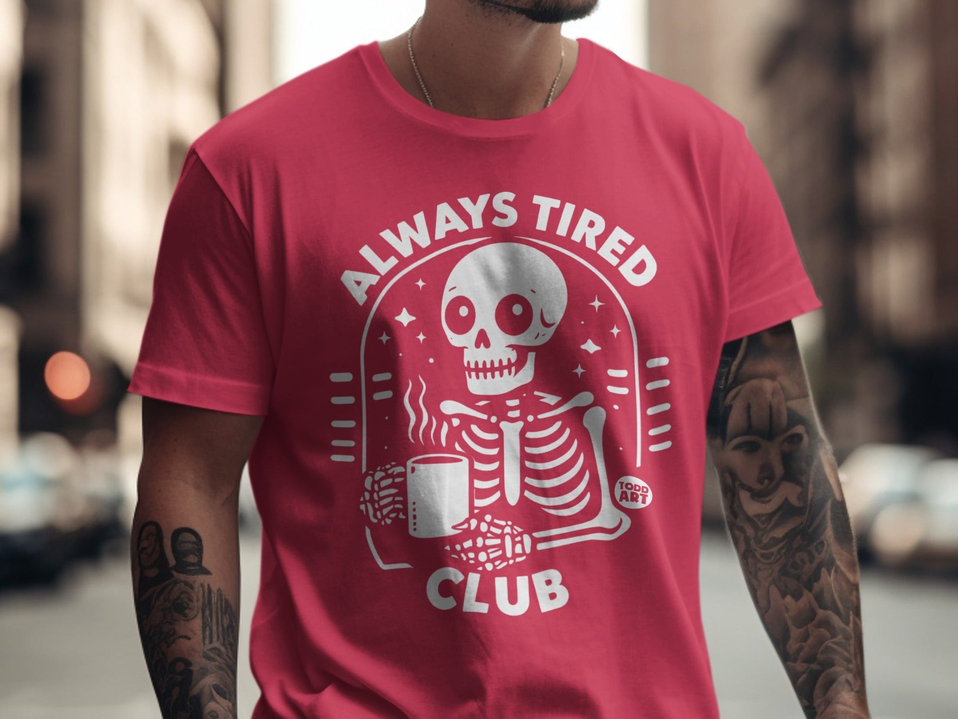 Red t-shirt with "Always Tired Club" text and skeleton holding a coffee mug.