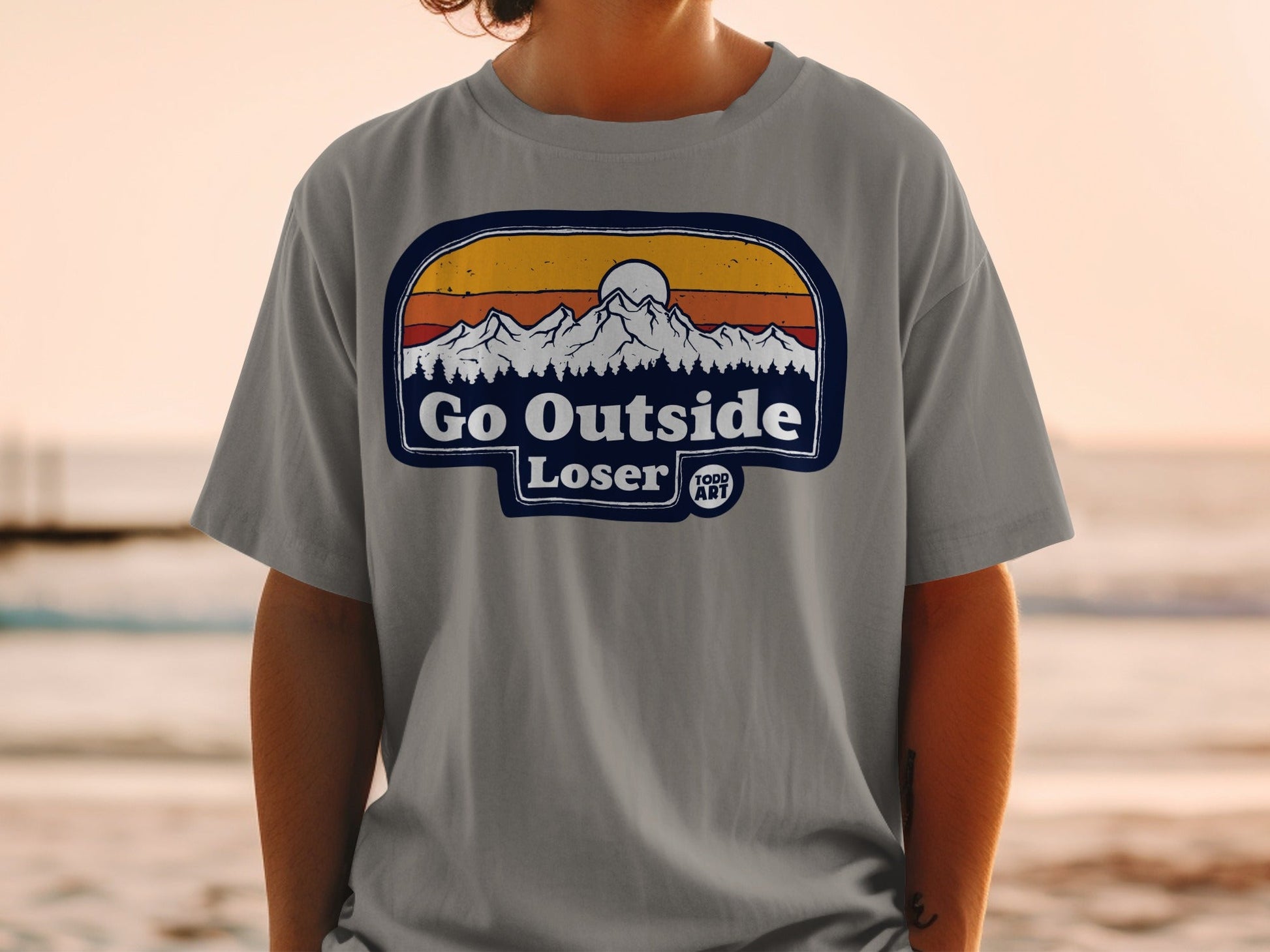 T-shirt with "Go Outside Loser" text and mountain sunset graphic.