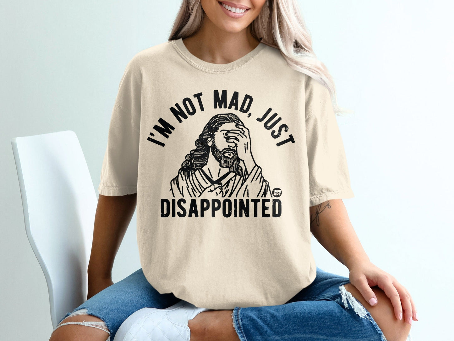 Cream t-shirt with black text "I'M NOT MAD, JUST DISAPPOINTED" and Jesus graphic.