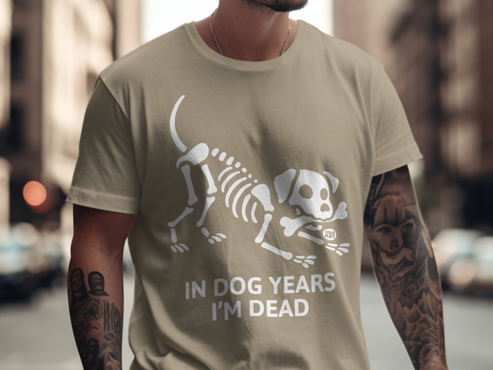 Tan t-shirt with white dog skeleton graphic and "IN DOG YEARS I'M DEAD" text.