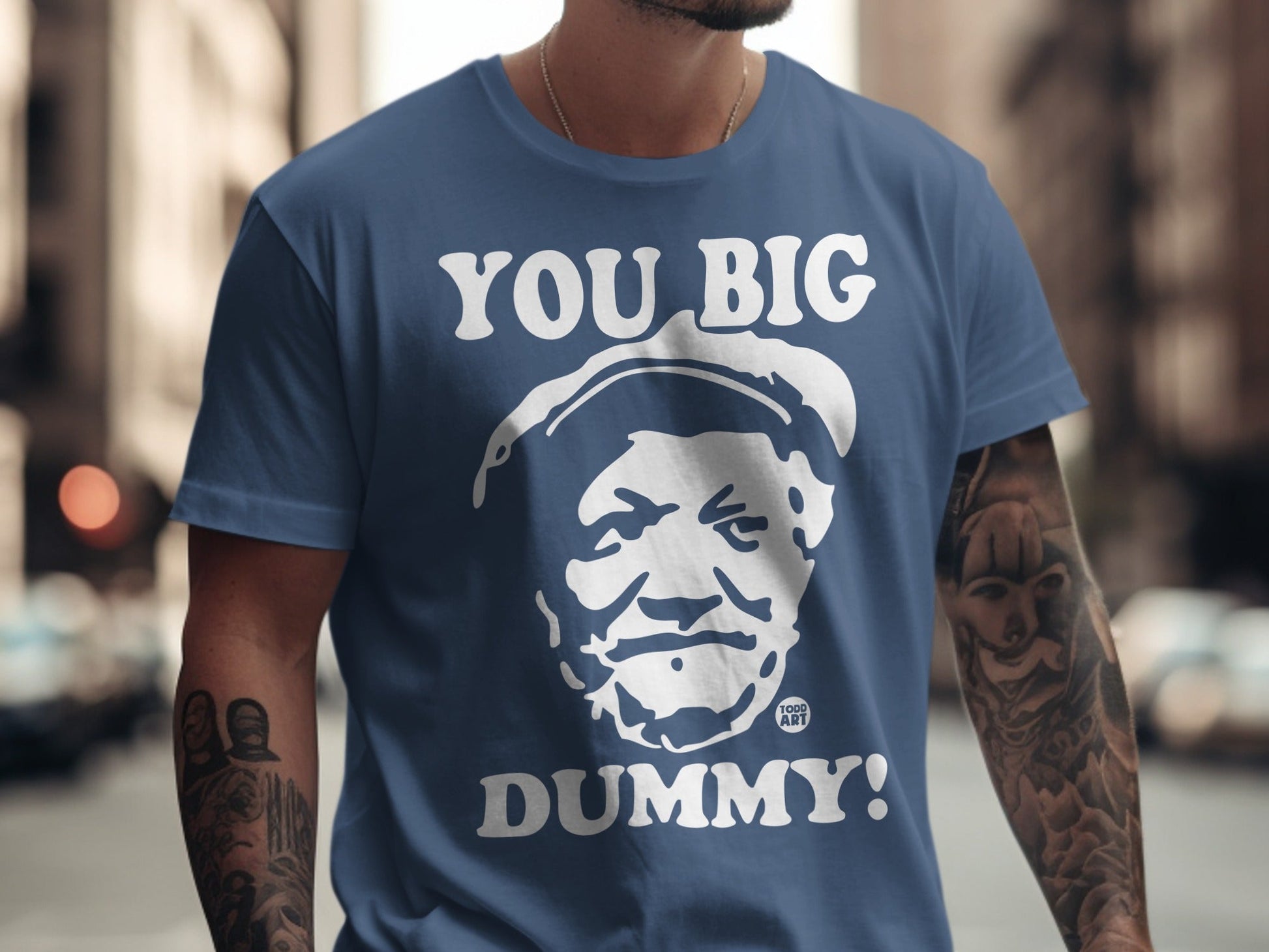 Blue t-shirt with white text "YOU BIG DUMMY!" and a graphic of a man's face.