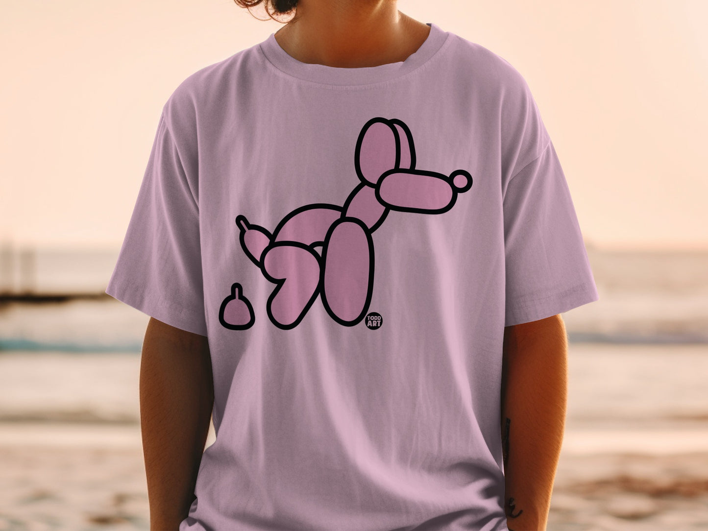 Pink balloon dog and poop graphic on a light purple t-shirt.