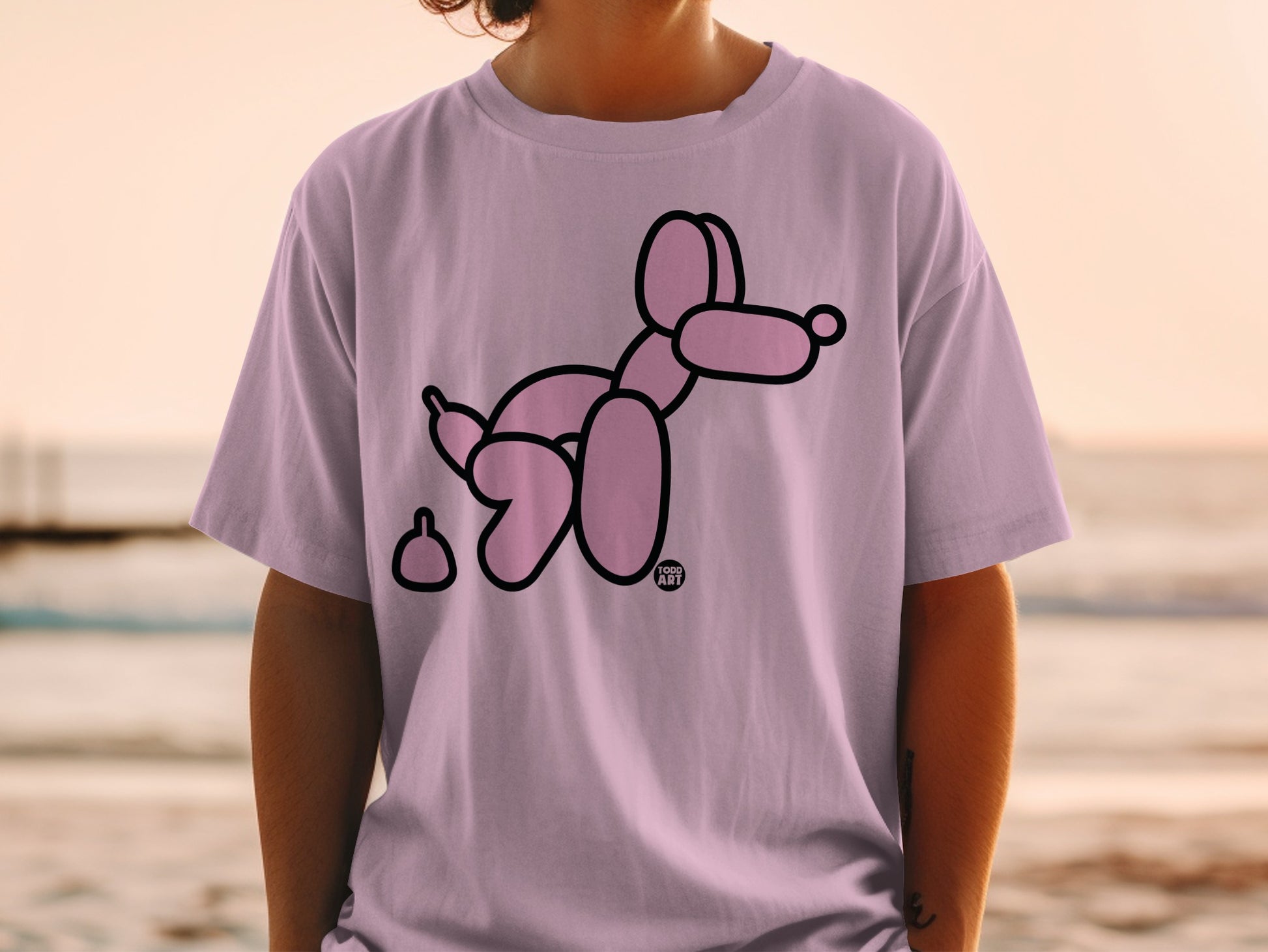 Pink balloon dog and poop graphic on a light purple t-shirt.