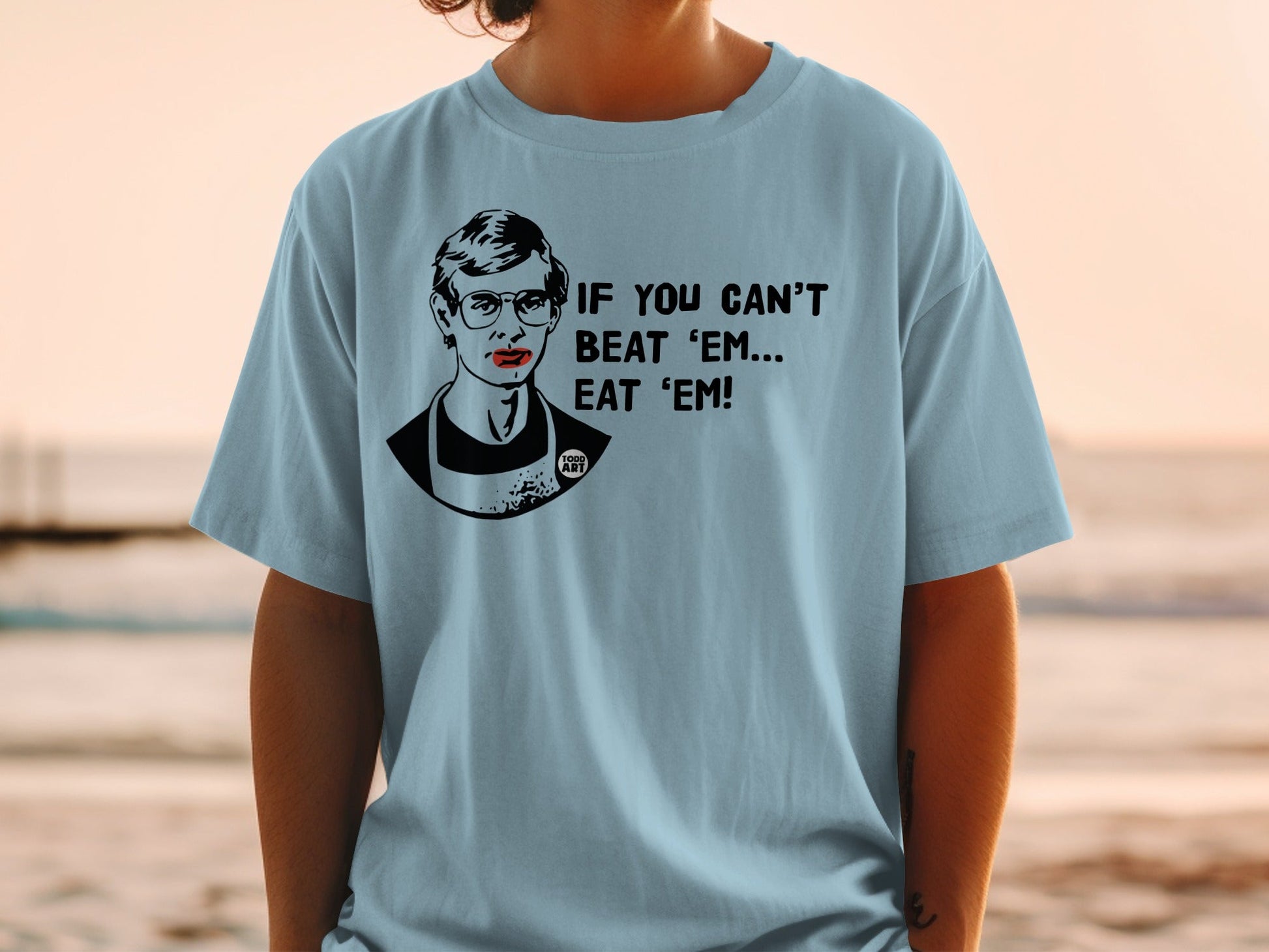 Light blue t-shirt with a black and white portrait and text: "IF YOU CAN'T BEAT 'EM... EAT 'EM!"