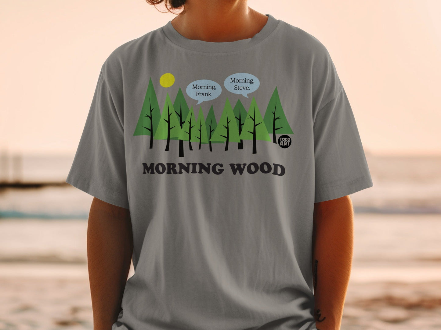 Gray t-shirt with trees, sun, and speech bubbles saying "Morning, Steve." and "Morning, Frank."