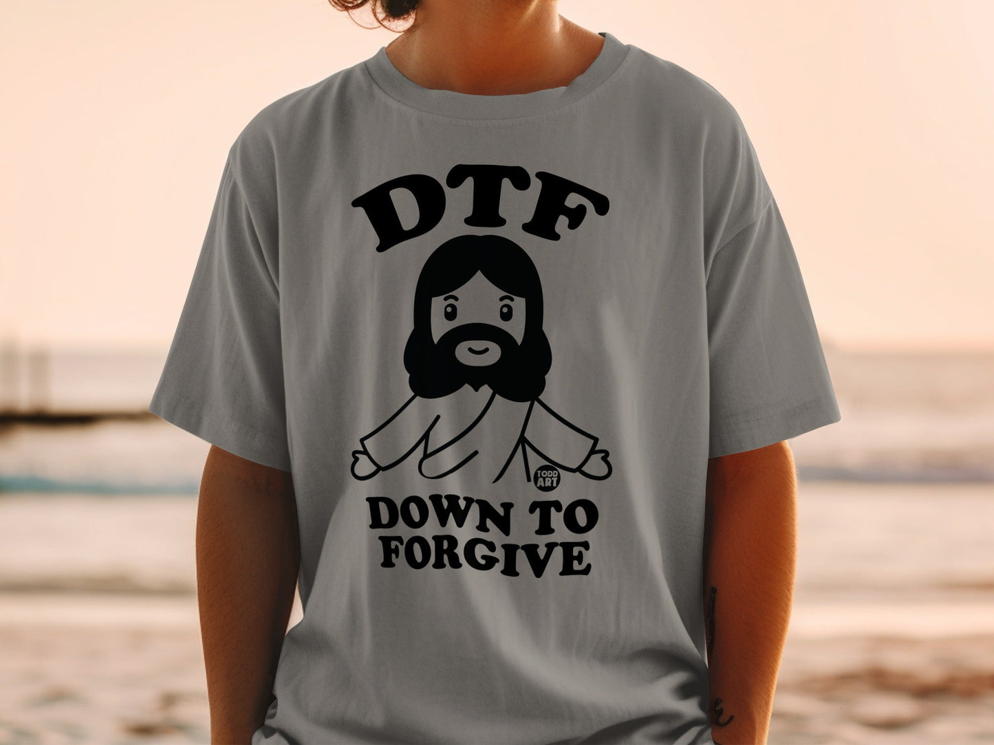 Grey t-shirt with cartoon Jesus graphic, "DTF DOWN TO FORGIVE" text.