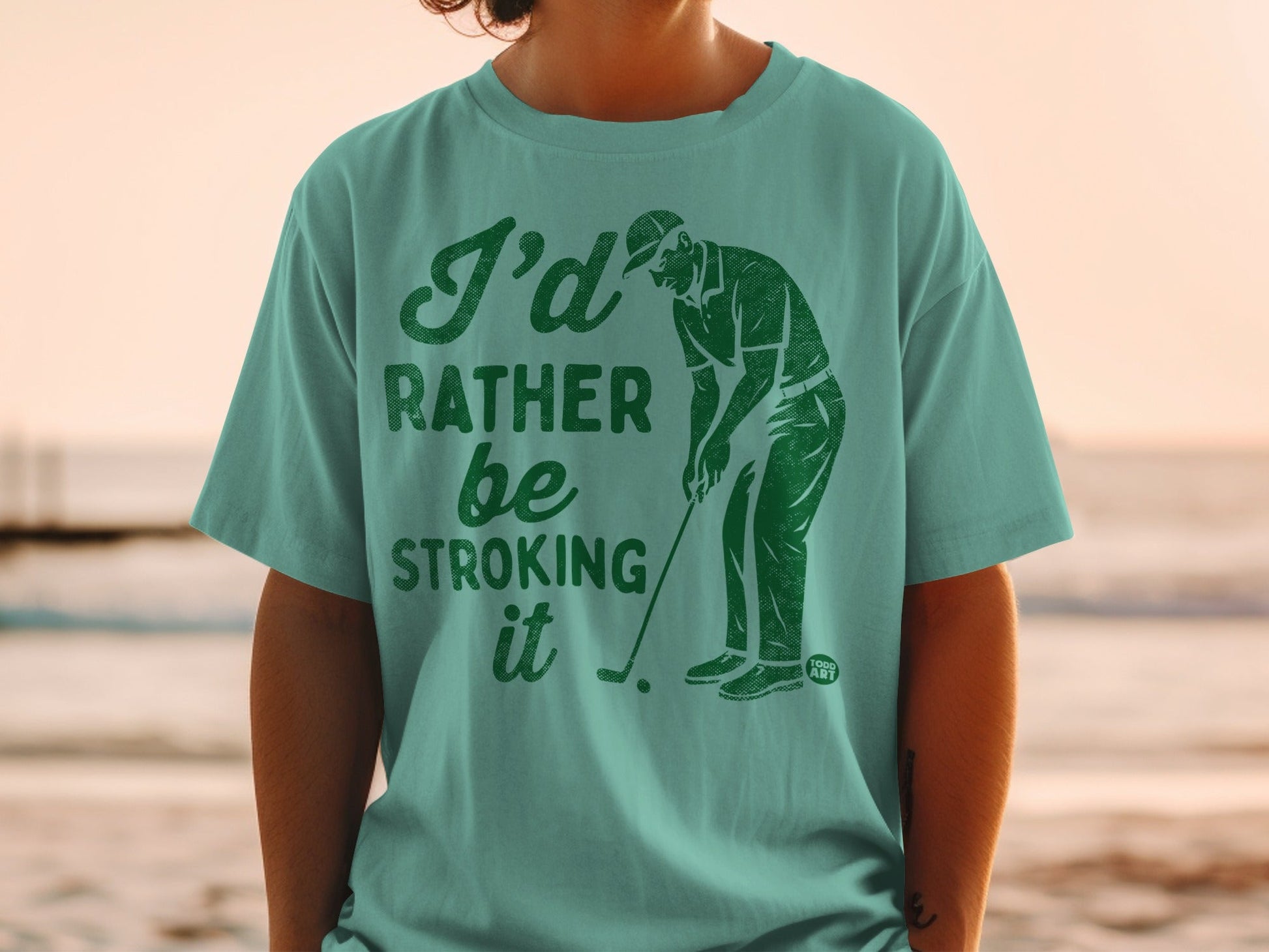 Teal t-shirt with "I'd rather be stroking it" text and golfer graphic.