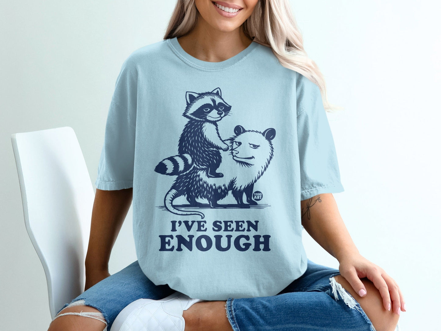 Light blue t-shirt with graphic of a raccoon riding a surprised opossum, text reads "I'VE SEEN ENOUGH".