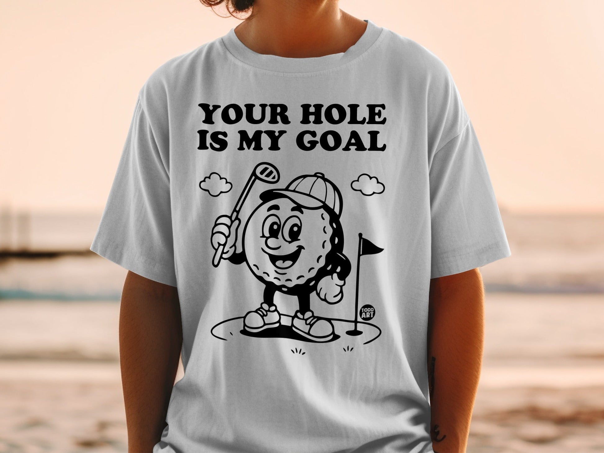T-shirt with cartoon golf ball character and "YOUR HOLE IS MY GOAL" text.