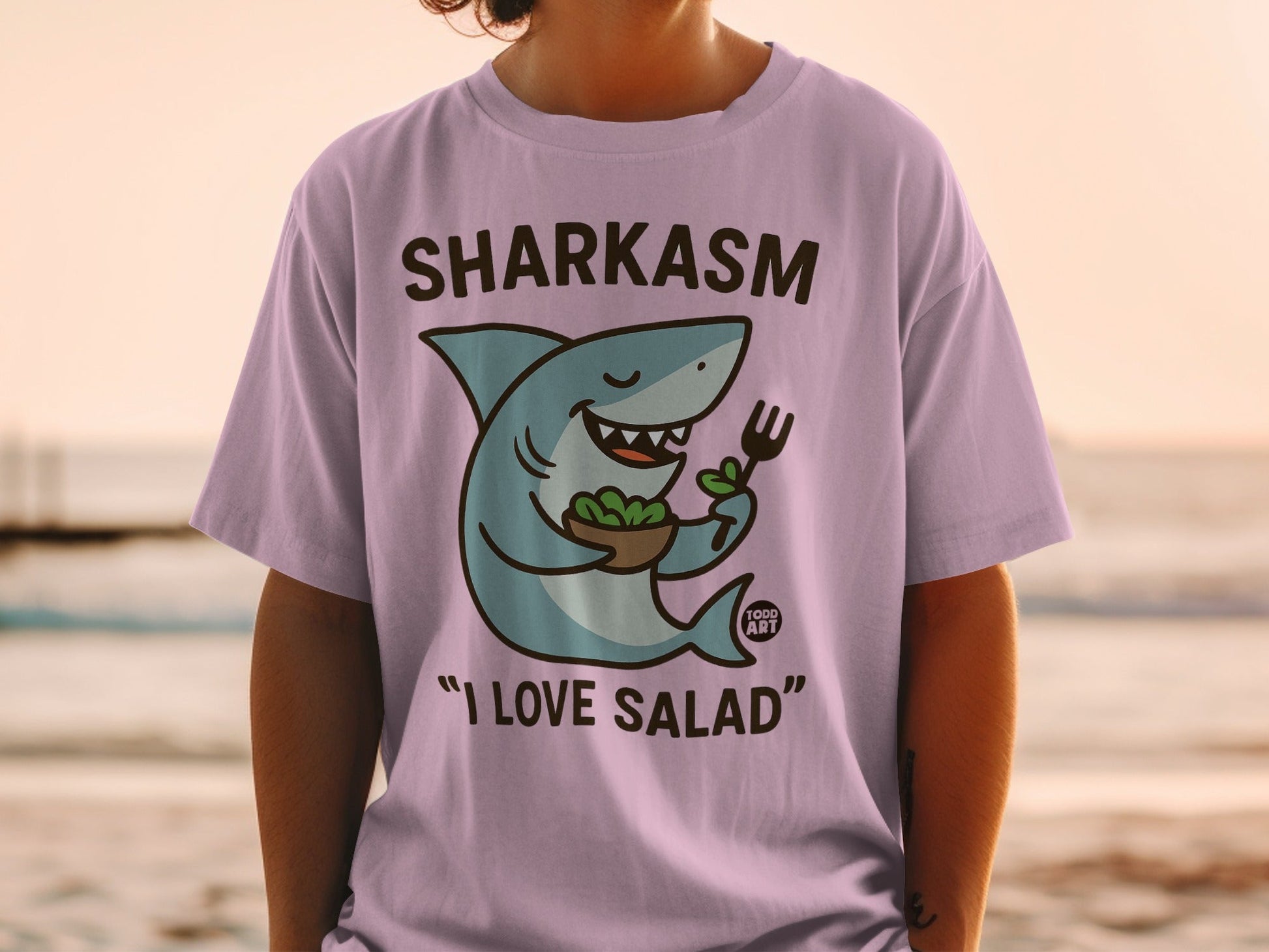 Purple t-shirt with cartoon shark holding a salad bowl and fork.