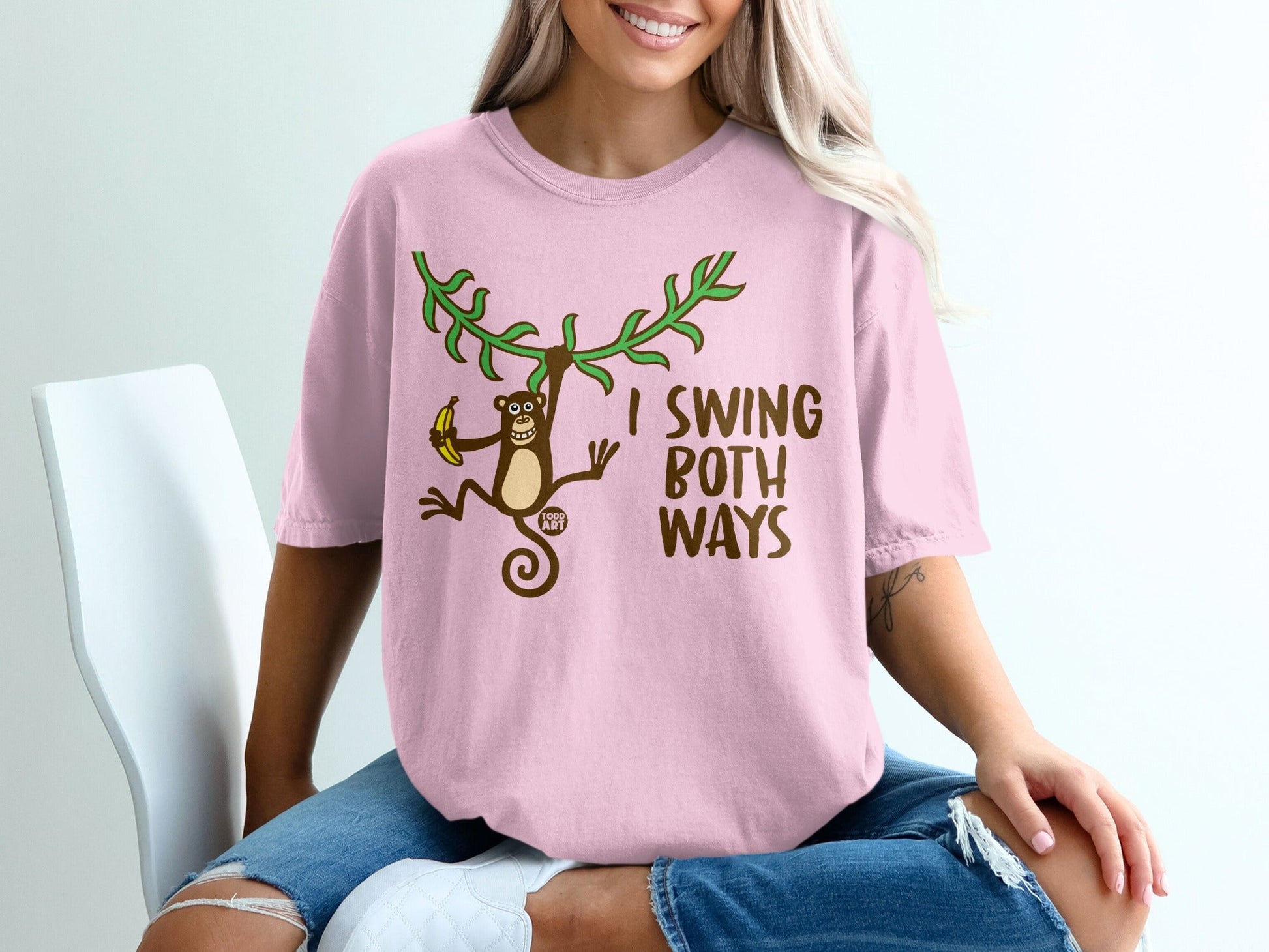 Pink t-shirt with monkey swinging on vine, text "I SWING BOTH WAYS".