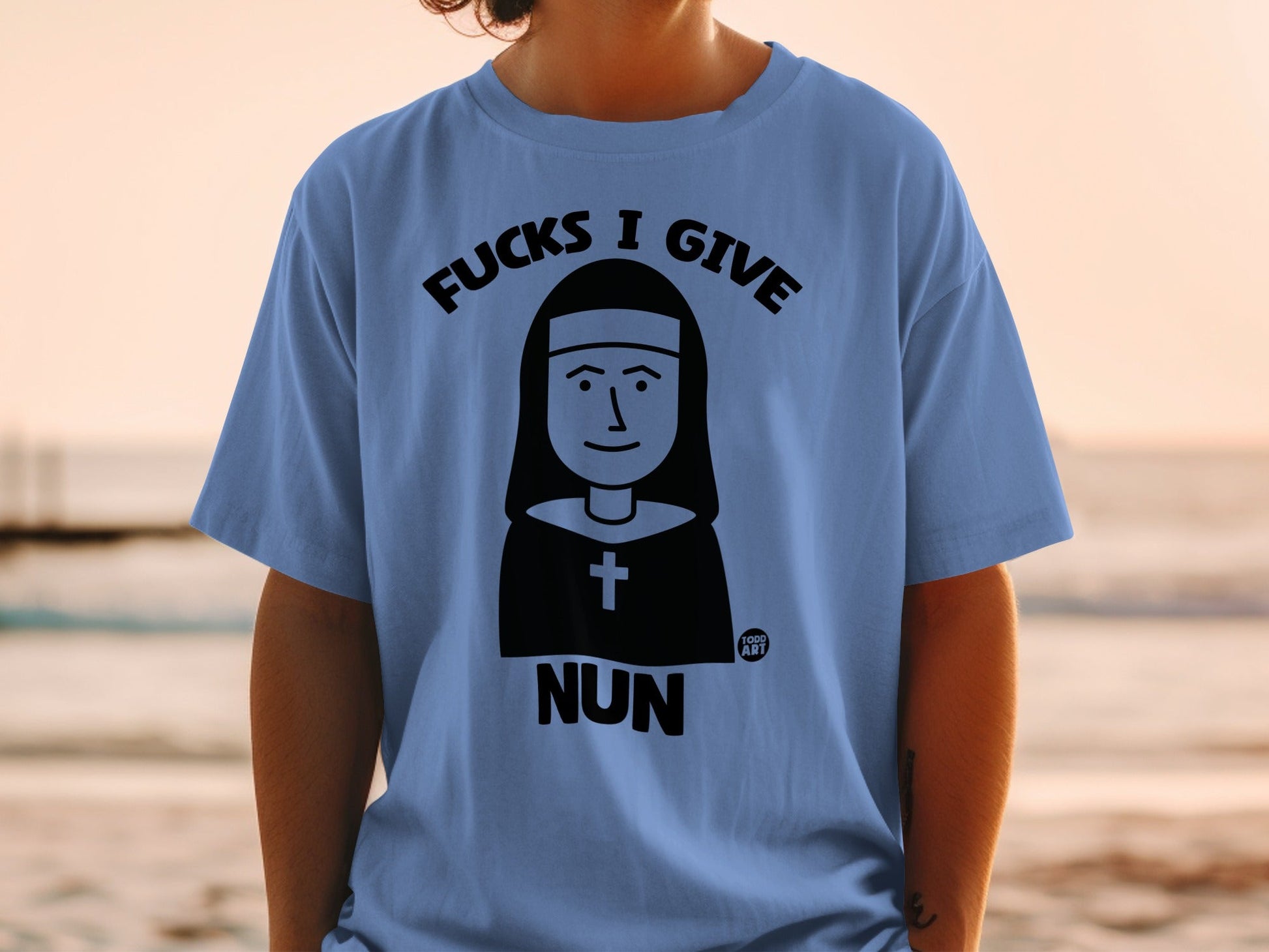 Light blue t-shirt with "Fucks I Give Nun" graphic featuring a nun illustration.