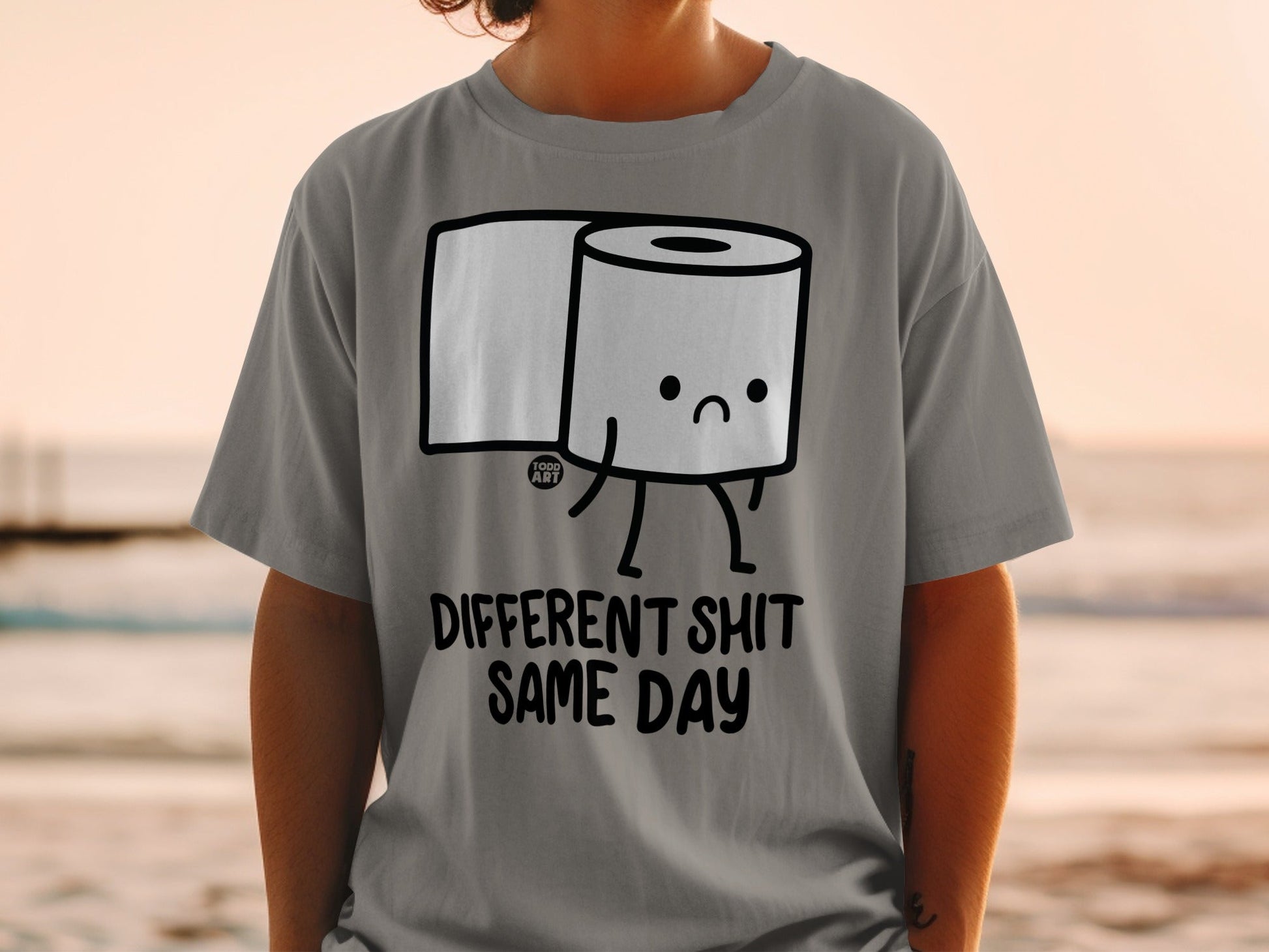 Gray t-shirt with cartoon toilet paper roll and "DIFFERENT SHIT SAME DAY" text.