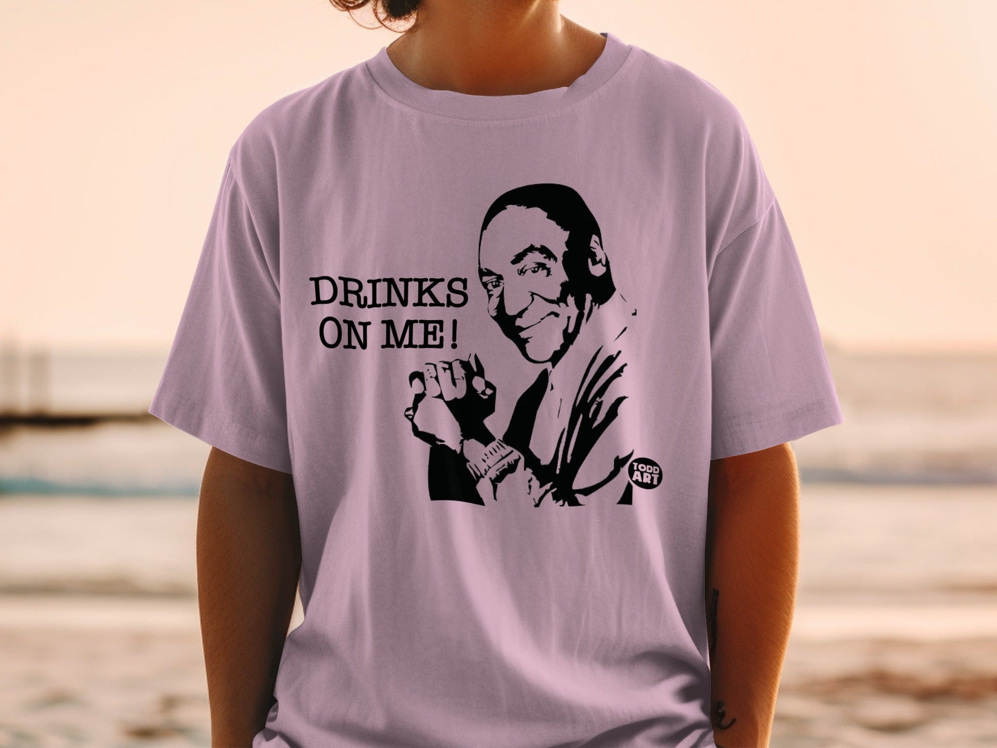 T-shirt with "DRINKS ON ME!" text and a caricature of a smiling man.