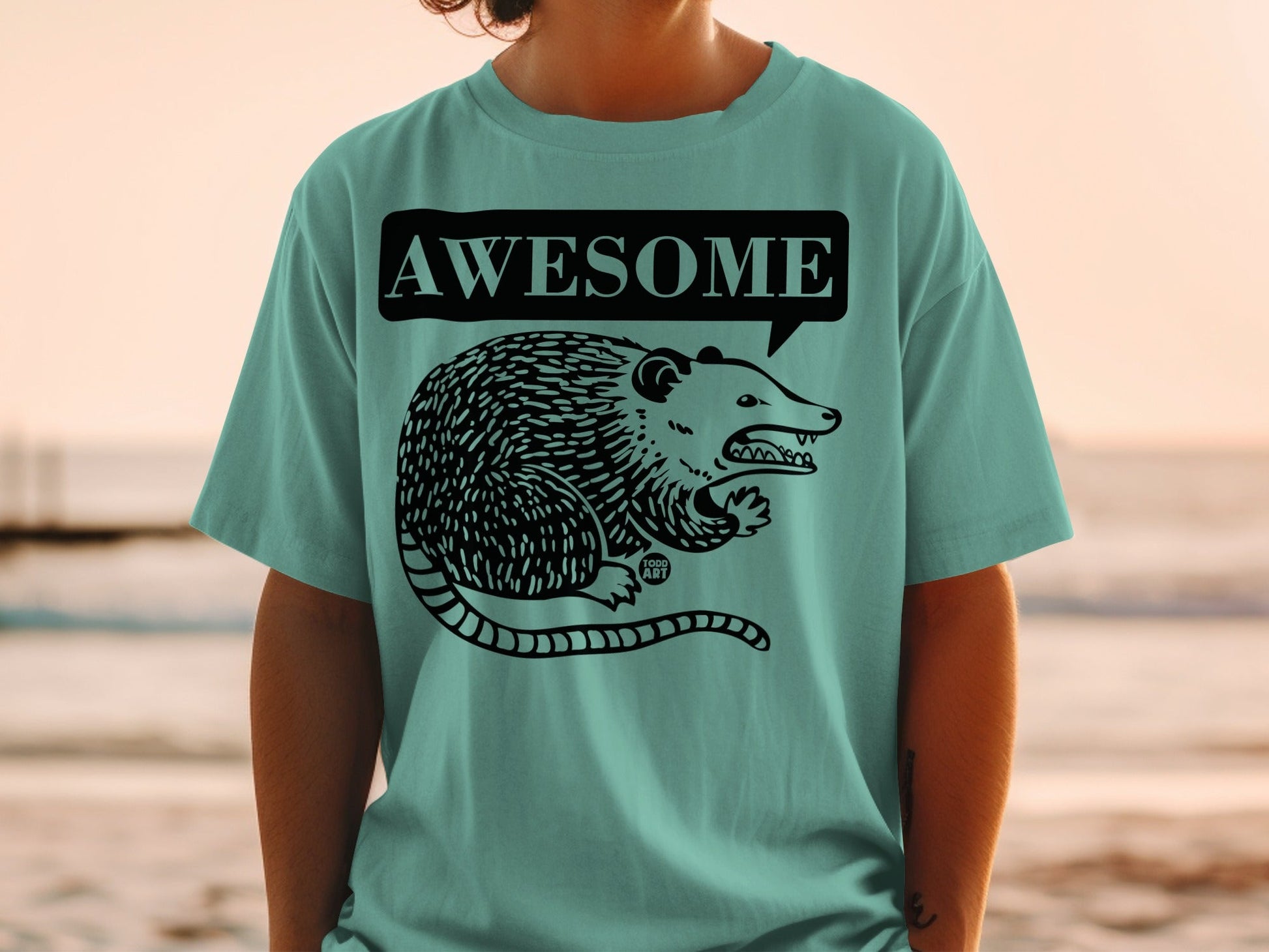Teal t-shirt with a cartoon possum and "AWESOME" speech bubble.